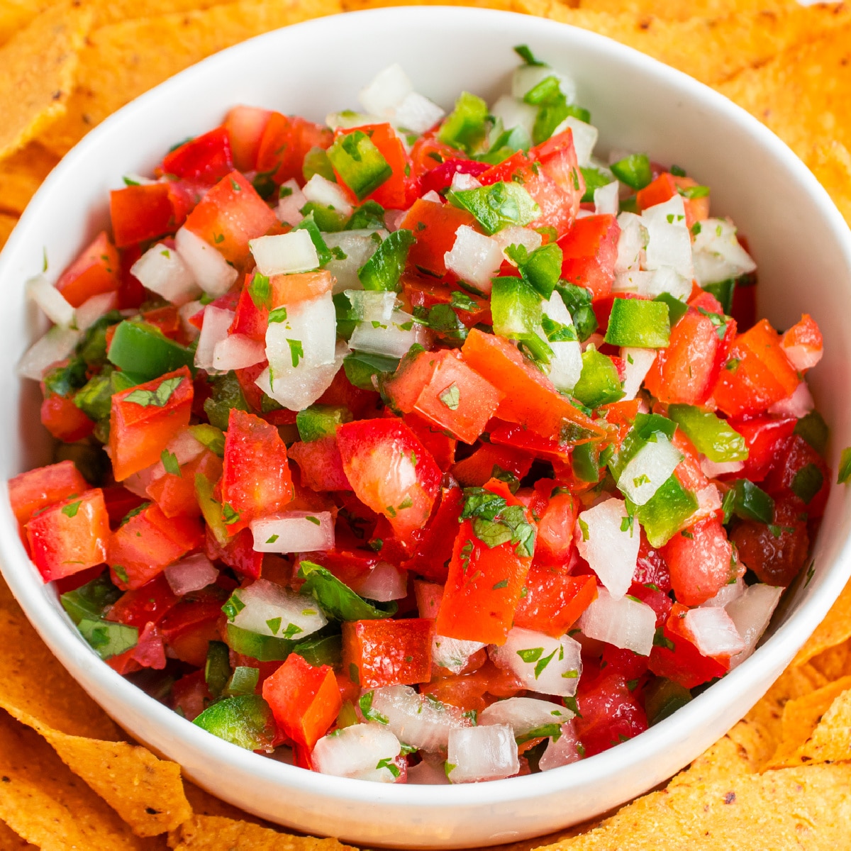 Square picture of a close-up bowl of Pico de Gallo shot from overhead. 