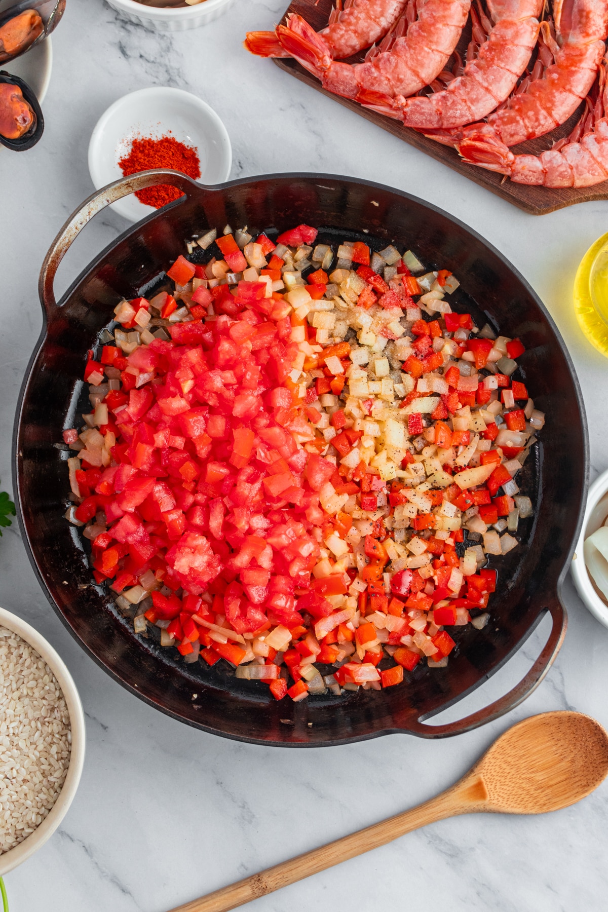 Adding diced tomato to sauteed vegetables.