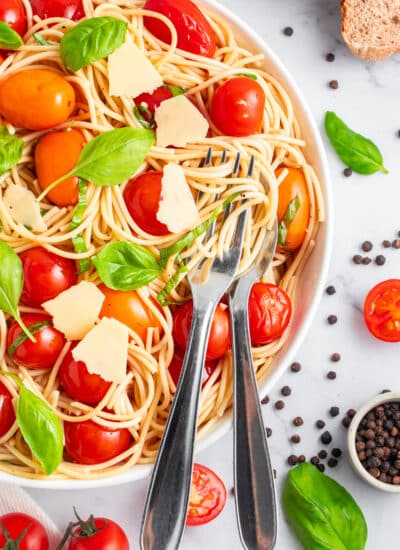 Overhead of fresh tomato pasta with a fork and spoon for serving.