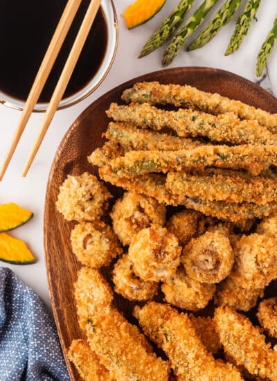 Vegetable Tempura on a plate with chopsticks and dipping sauce.