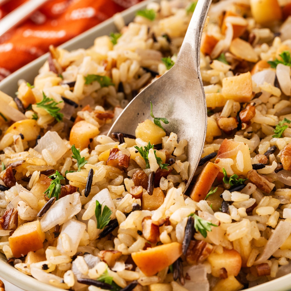 Square photo of a spoon going into a bowl of wild rice. 