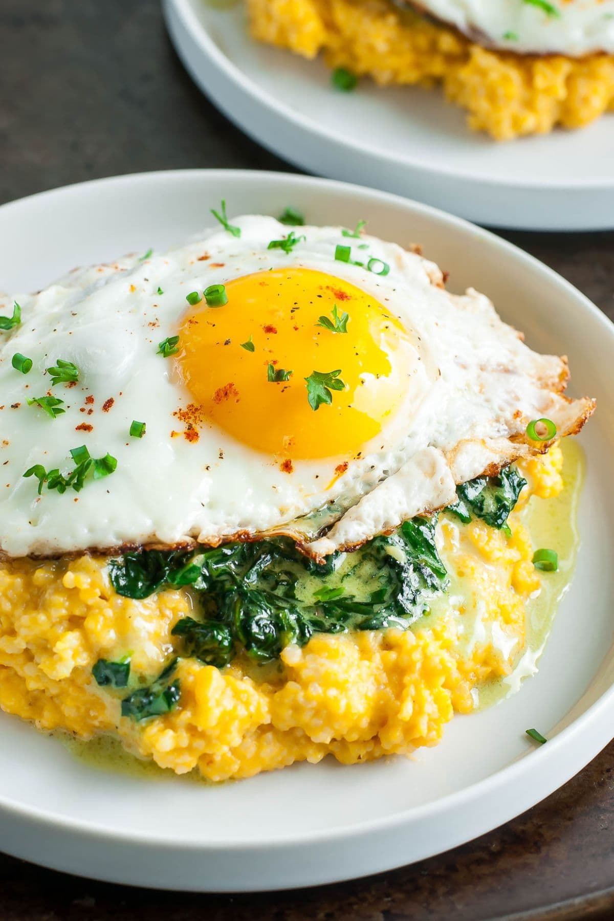 Plate full of brown butter pumpkin grits with an over easy egg on top.