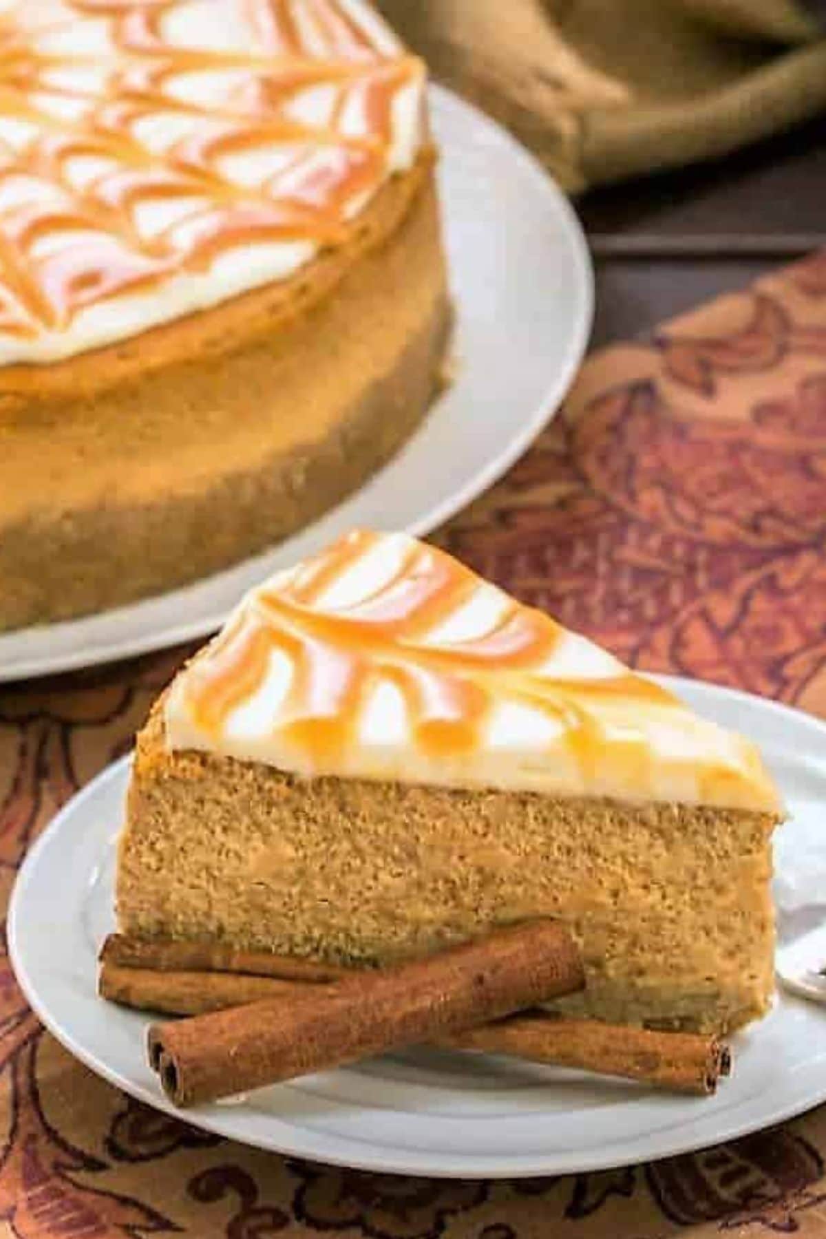 Slice of caramel topped pumpkin cheesecake on a small plate.