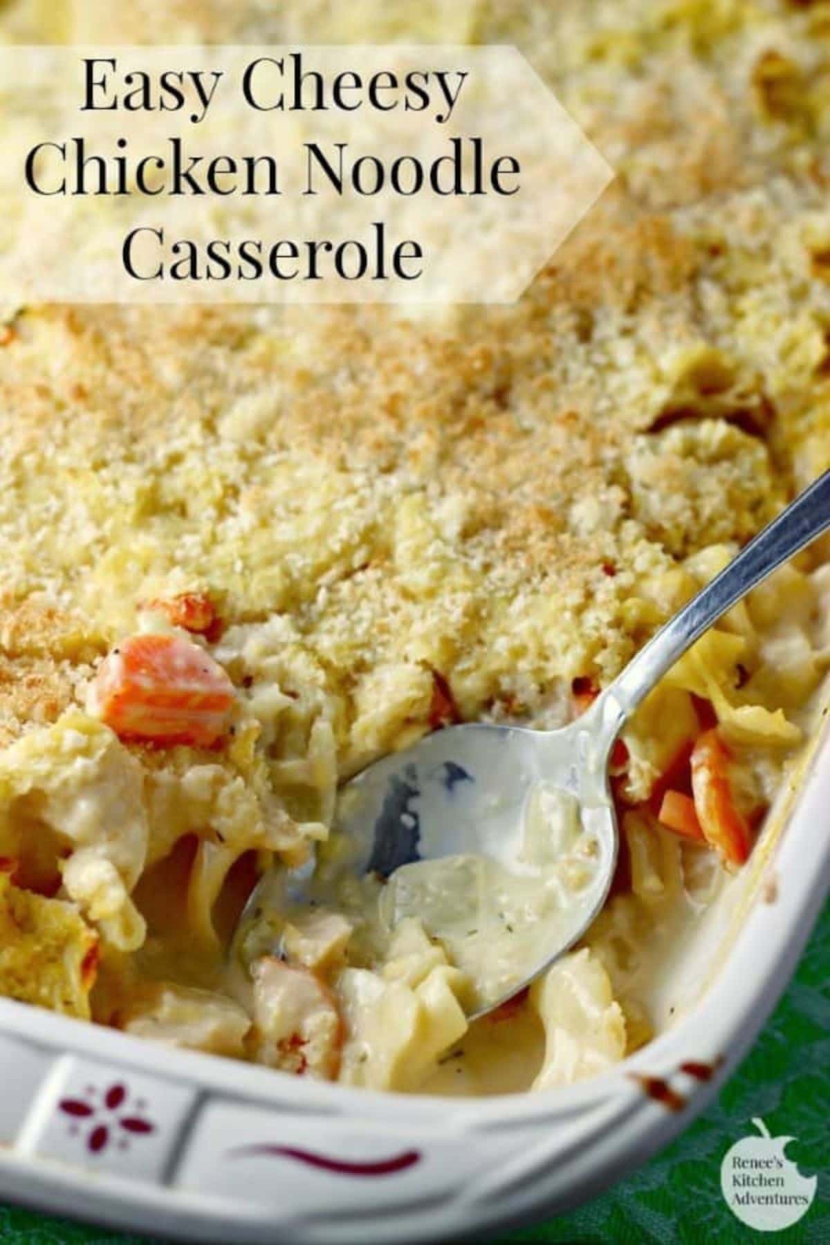 Cheesy chicken noodle casserole in a baking dish with a bite misisng.