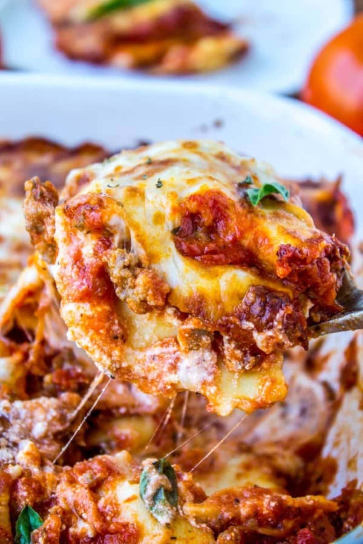 Slice of cheesy ravioli lasagna being removed from the casserole dish.