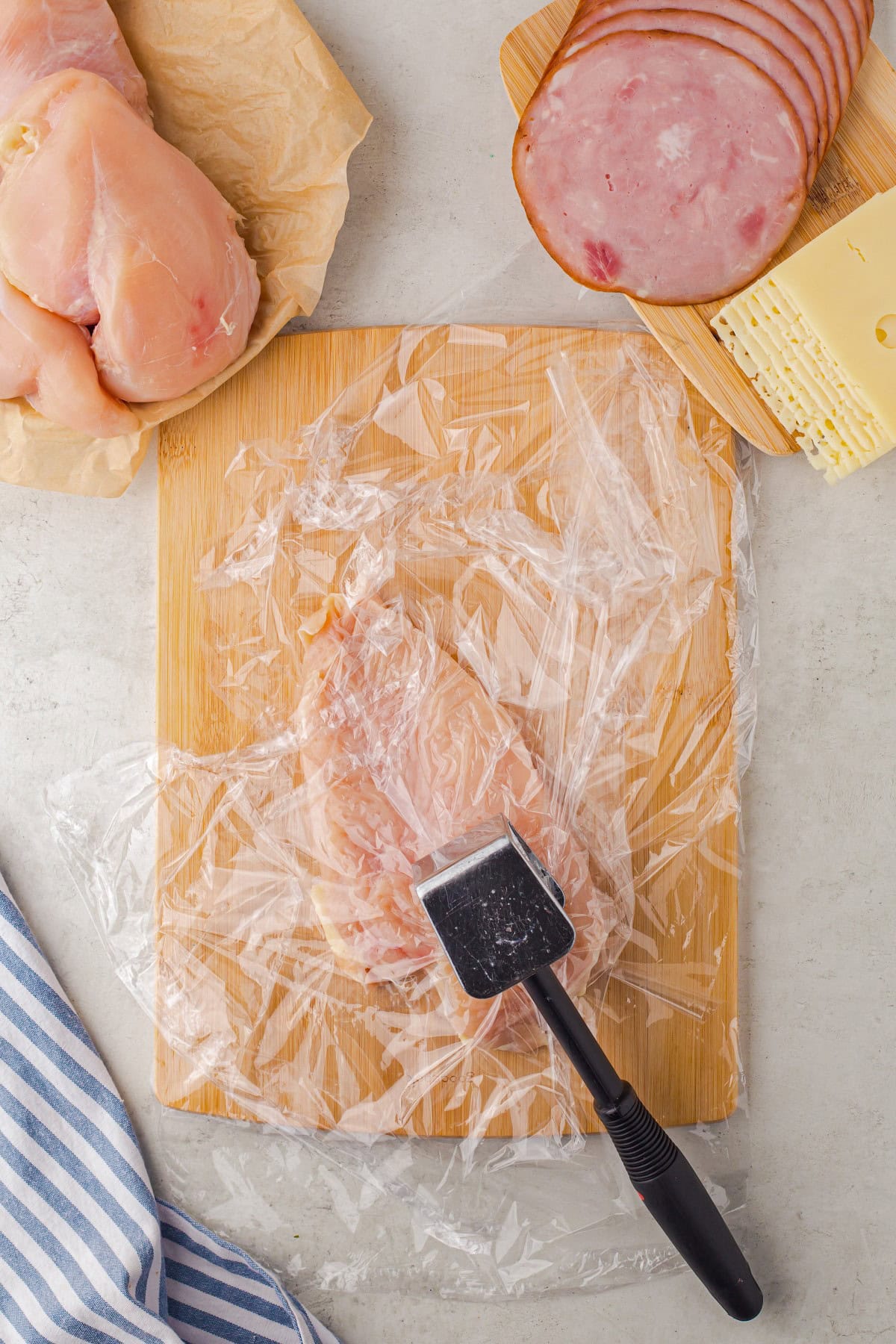 Pounding out the chicken under plastic wrap. 