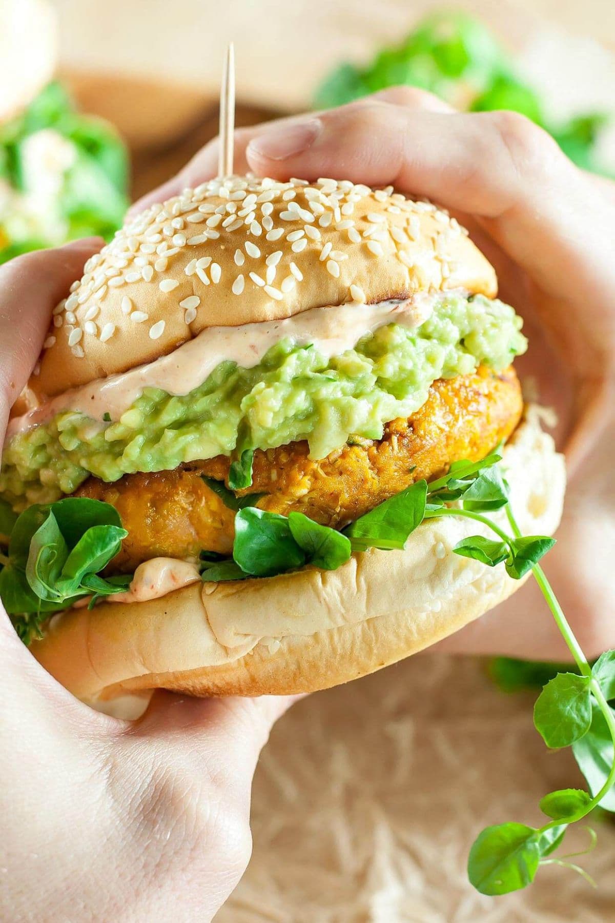 Chipotle pumpkin veggie burger held in the air in a woman's hand.