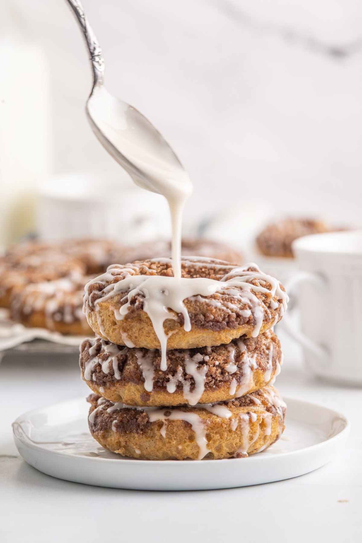 Pouring icing on three stacked donuts. 