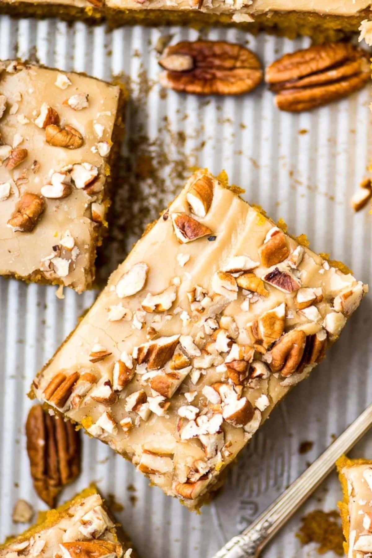 Slices of pecan praline pumpkin cake on a baking sheet.