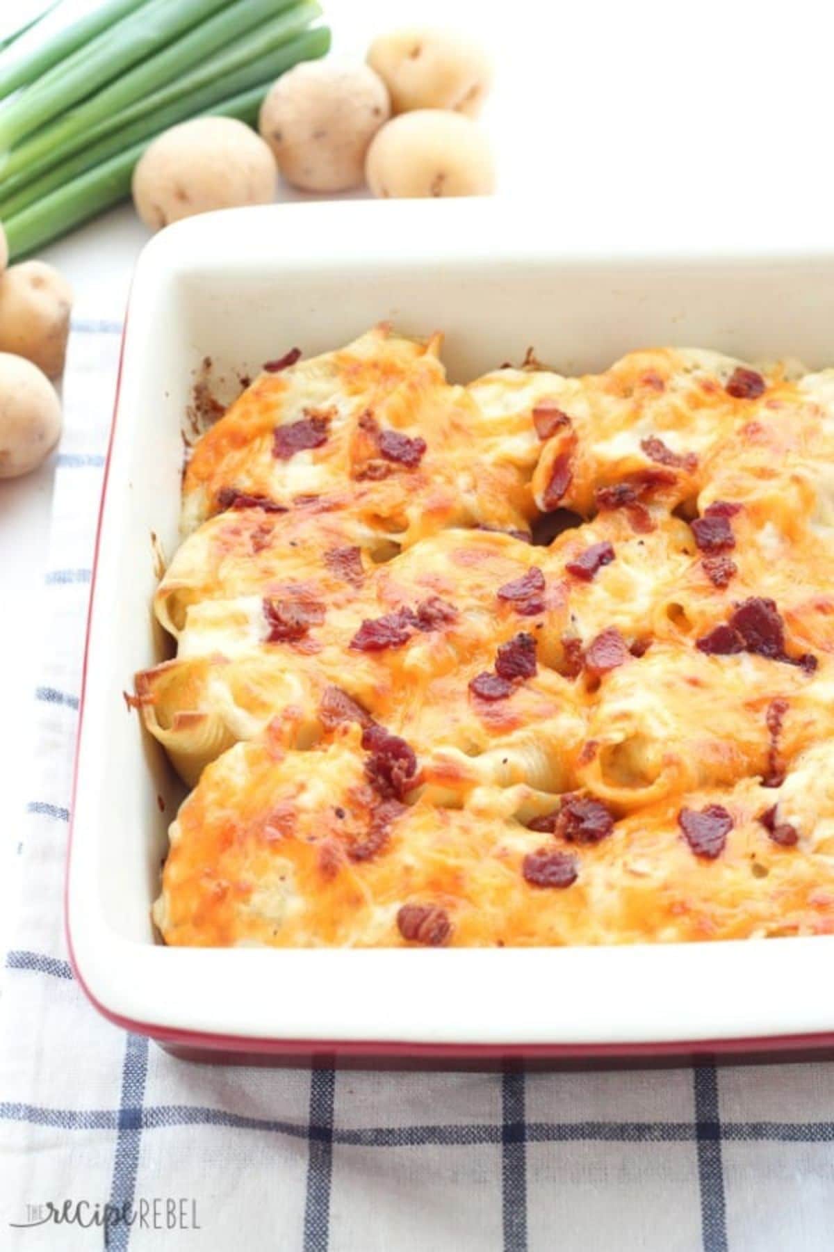 Baking dish full of perogi stuffed shells topped with bacon bits.