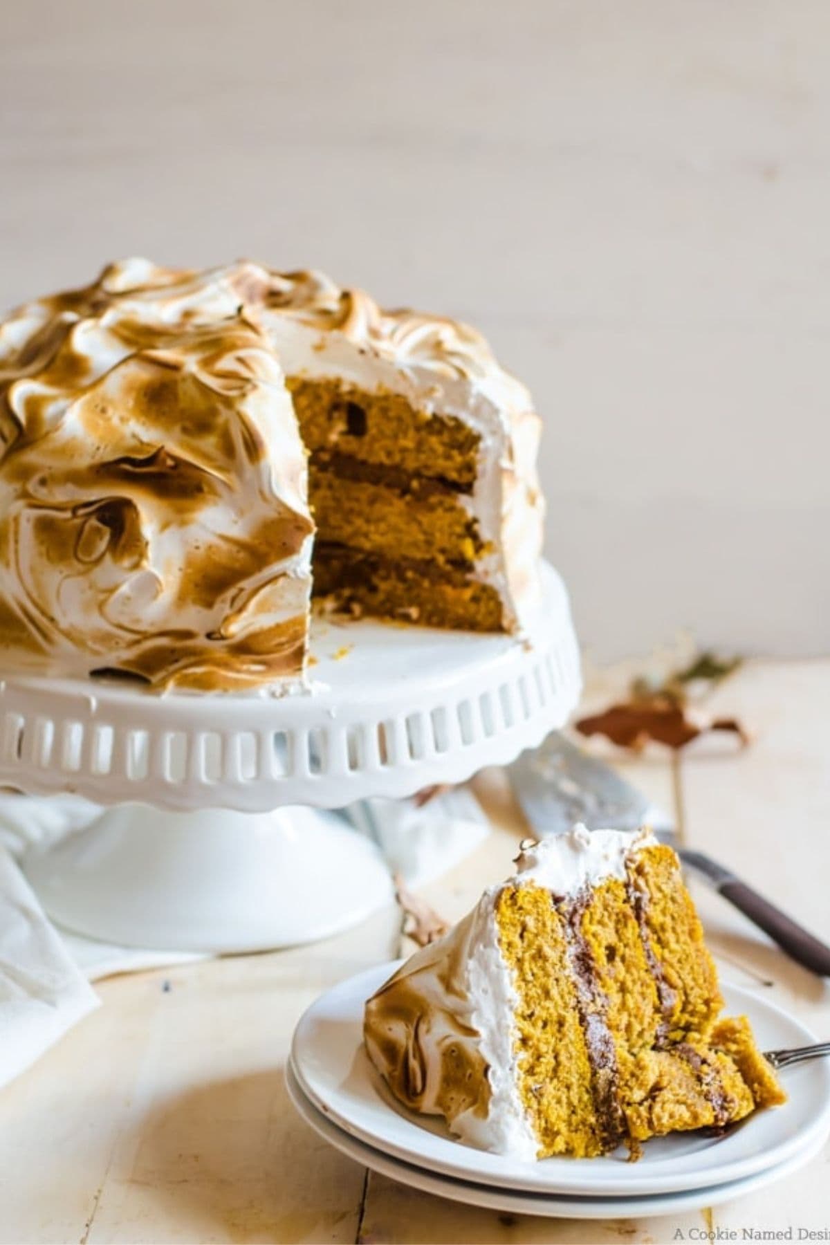 Slice of pumpkin cake with ginger chocolate and meringue on a small plate.