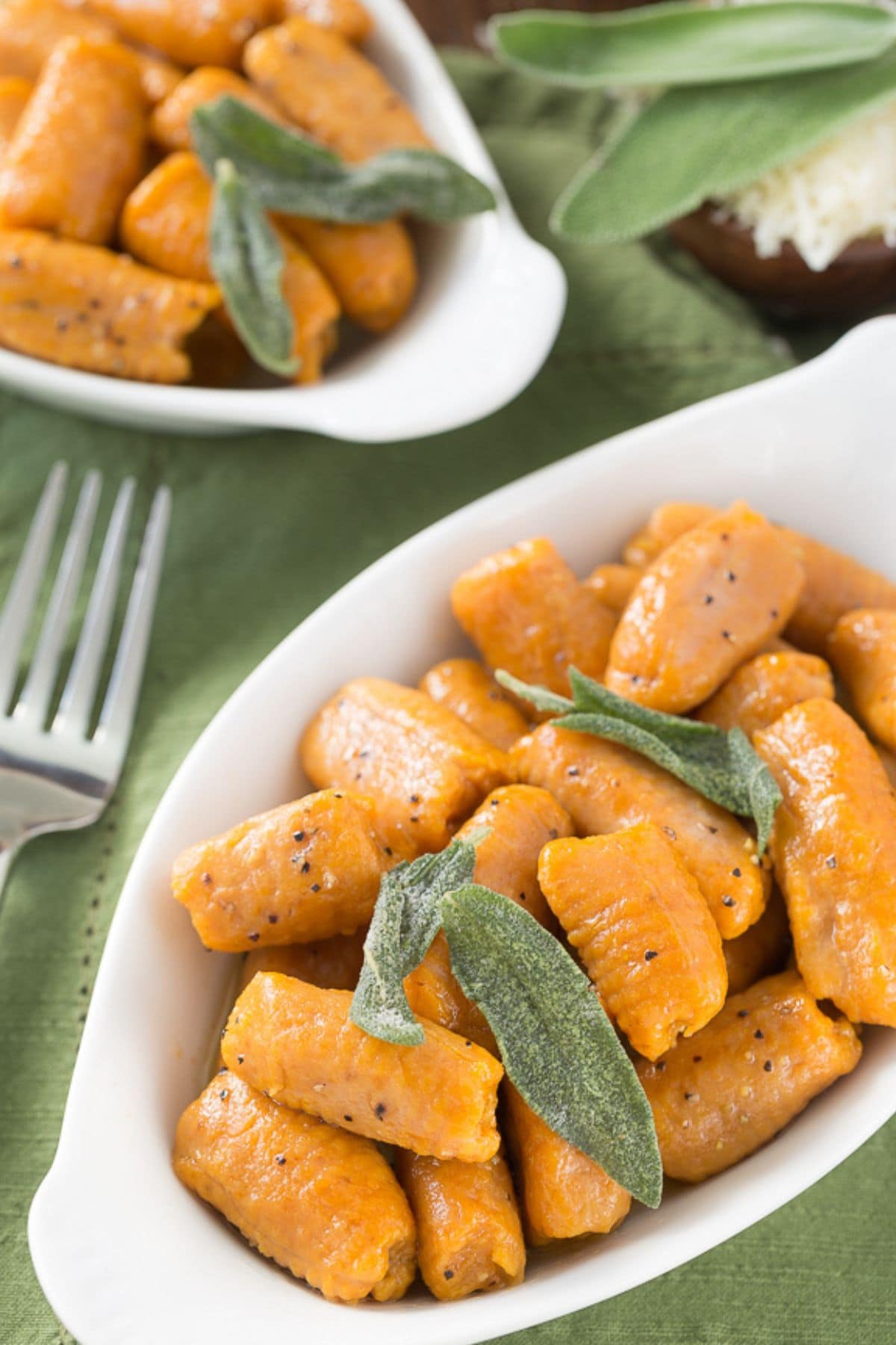 Small bowl filled with pumpkin gnocchi topped with sage.