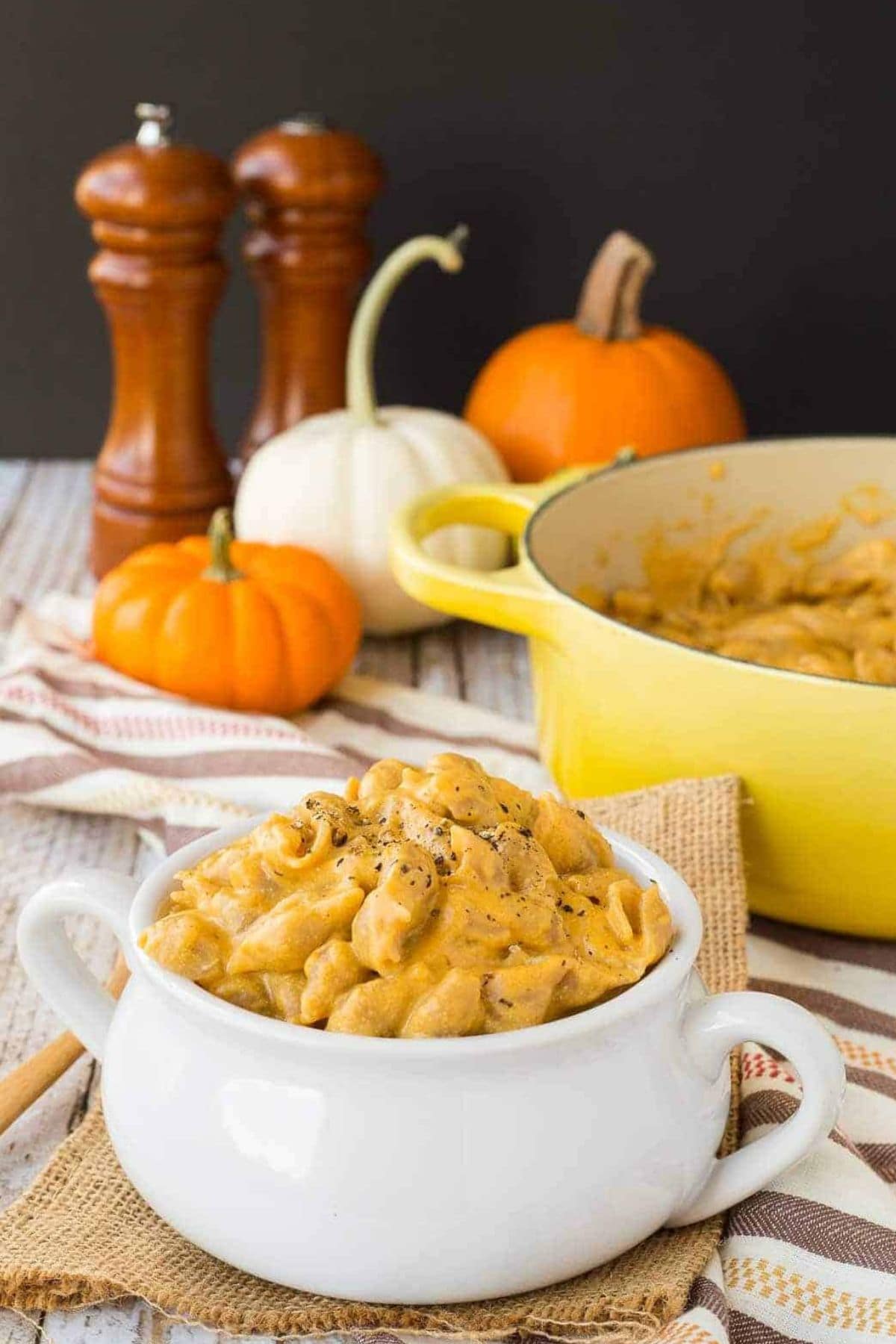 Small bowl with handles filled with pumpkin macaroni and cheese.