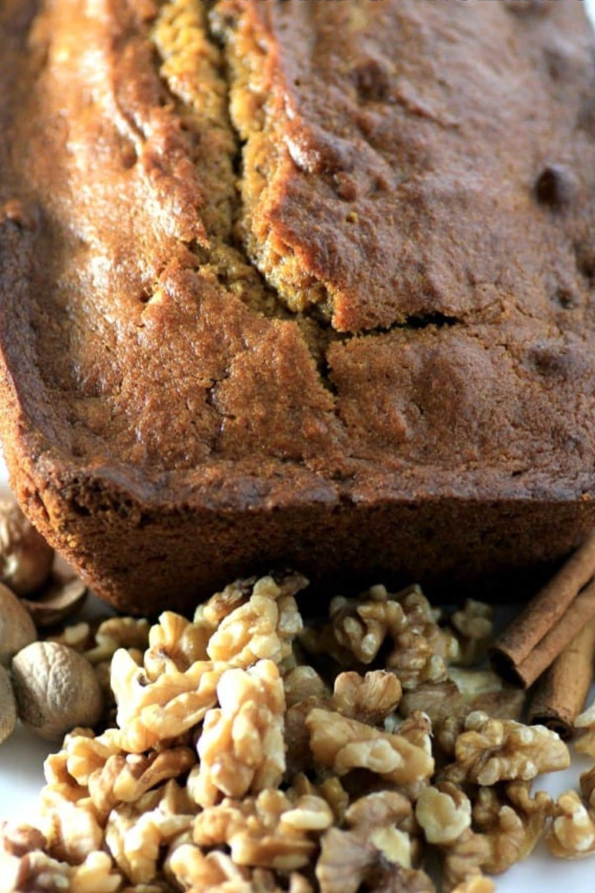 Pumpkin walnut loaf on a counter with walnuts.