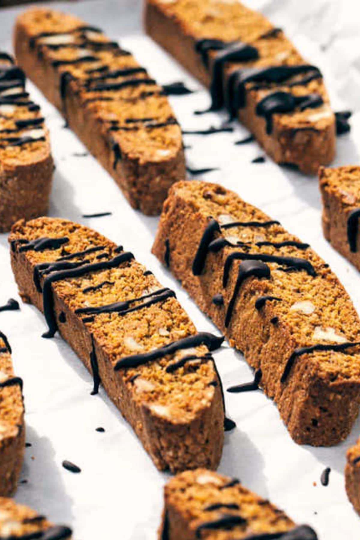 Pieces of pumpkin pecan biscotti on a parchment lined baking sheet.