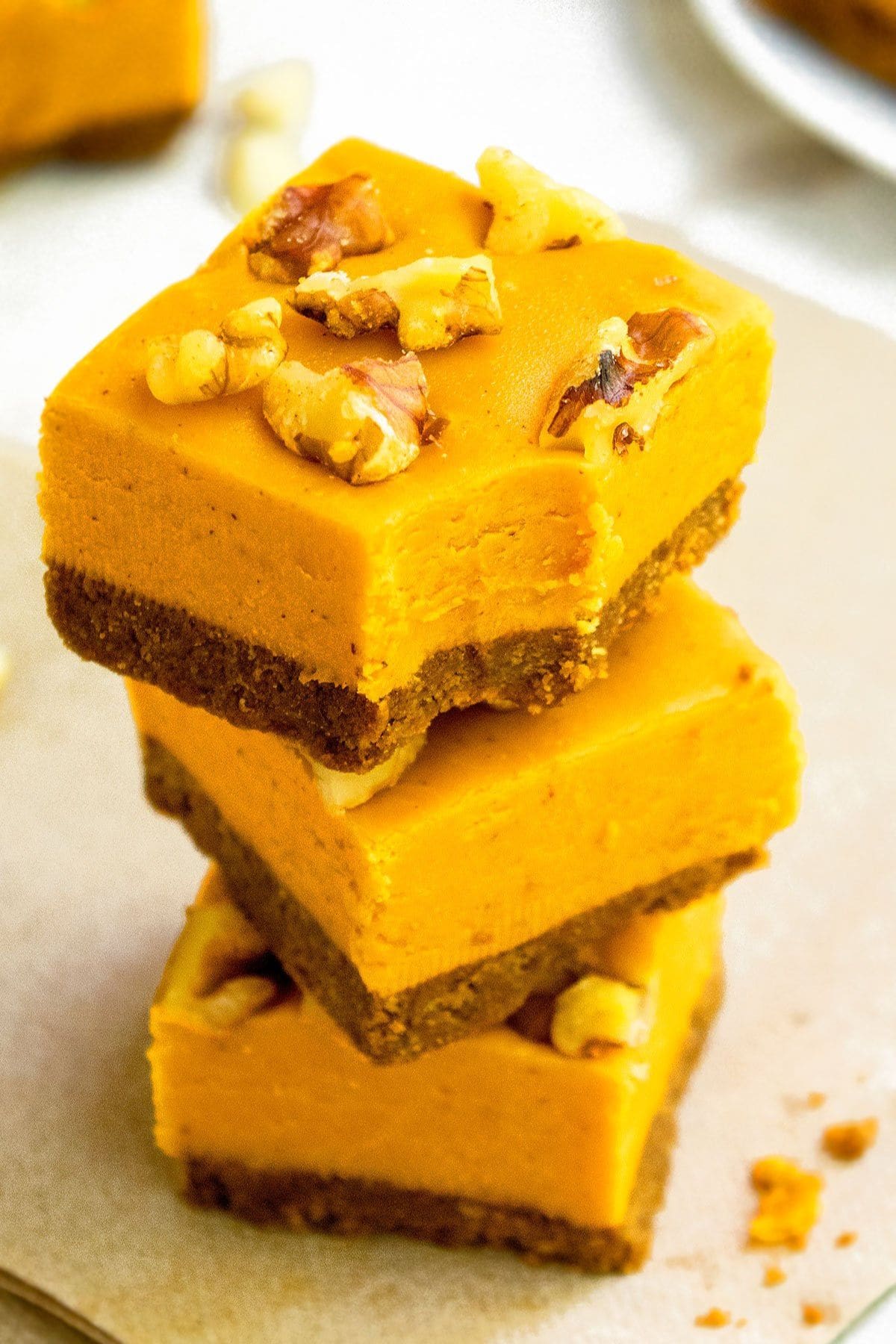 Three pieces of pumpkin pie fudge stacked on top of each other, the top one has a bite missing.