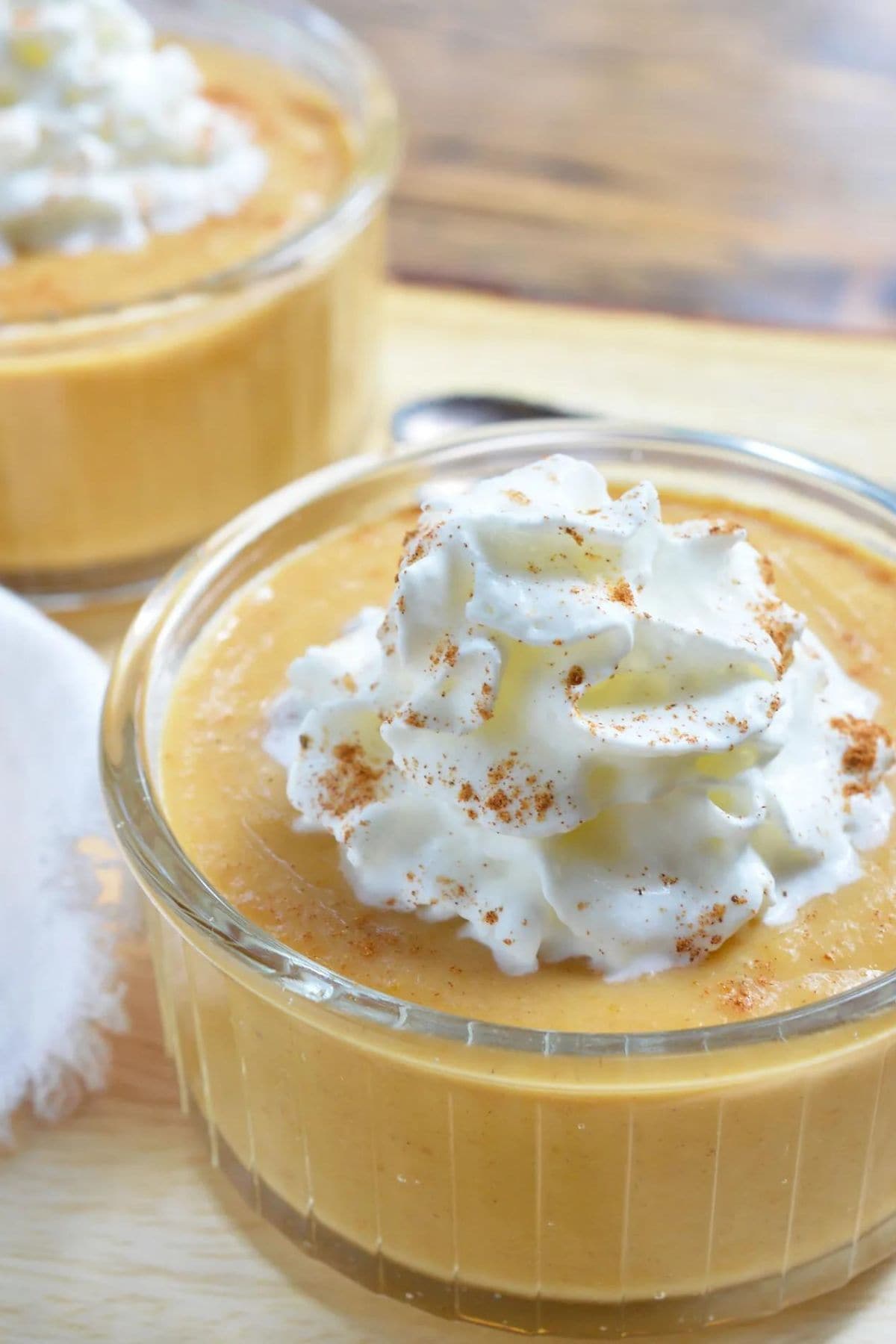 Small bowl full of pumpkin pie pudding topped with whipped cream.