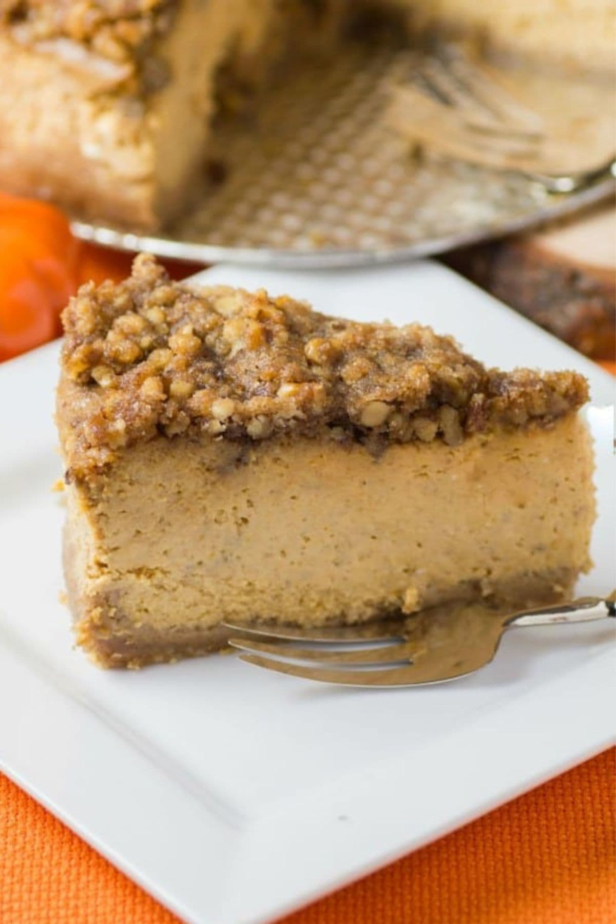 Slice of streusel topped pumpkin cheesecake on a square plate.