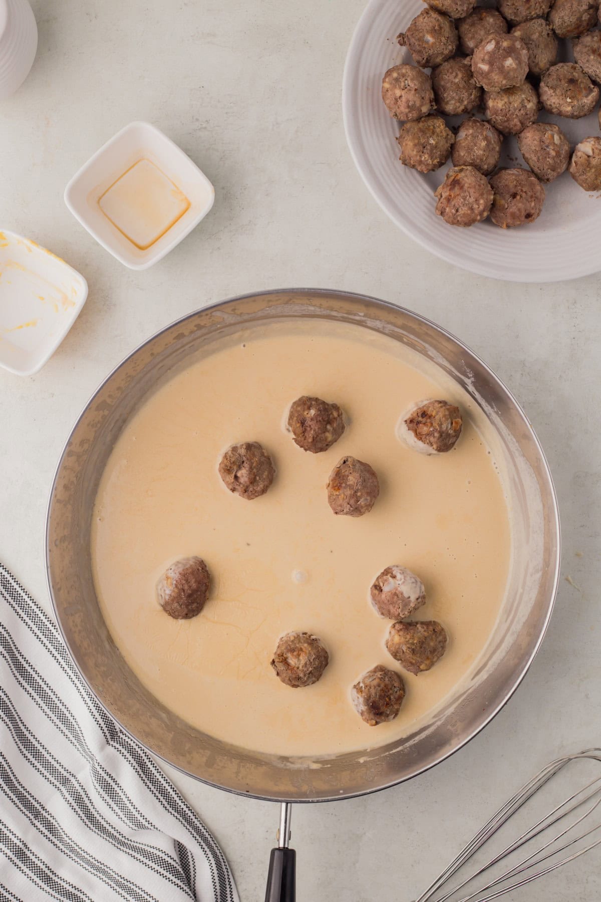 Adding meatballs to the gravy. 