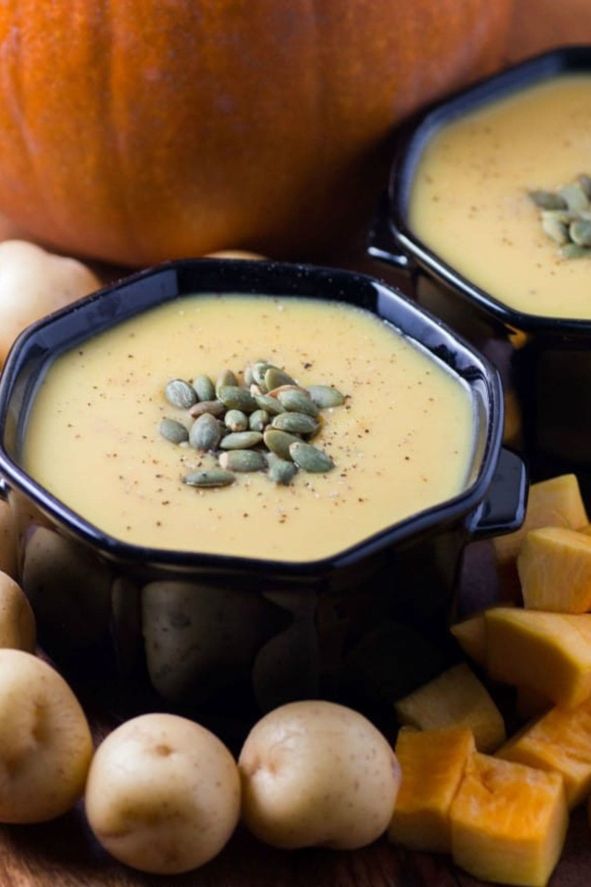 Bowl full of little potato pumpkin soup topped with pumpkin seeds.