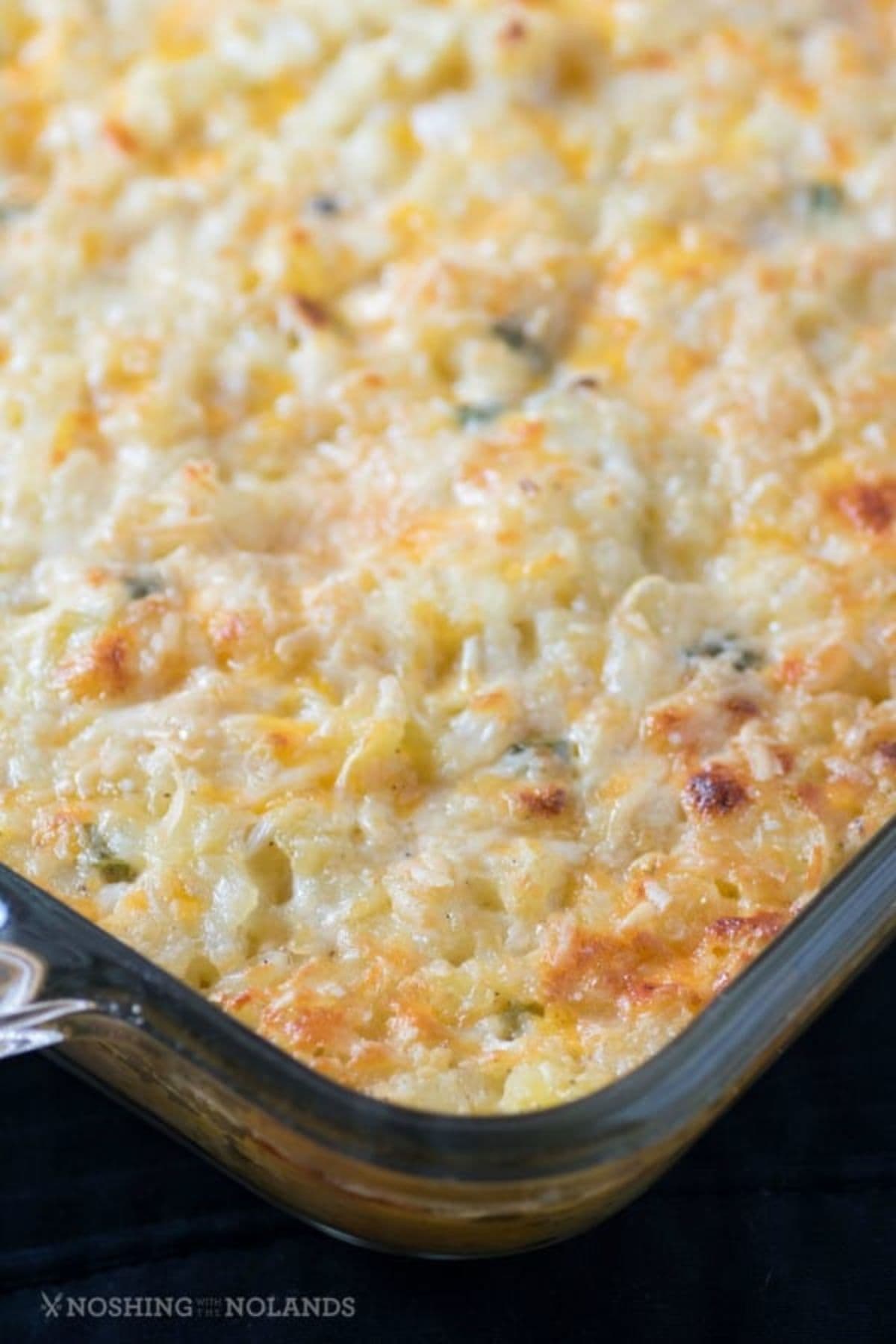 Baked cheddar hashbrown casserole in a glass casserole dish.