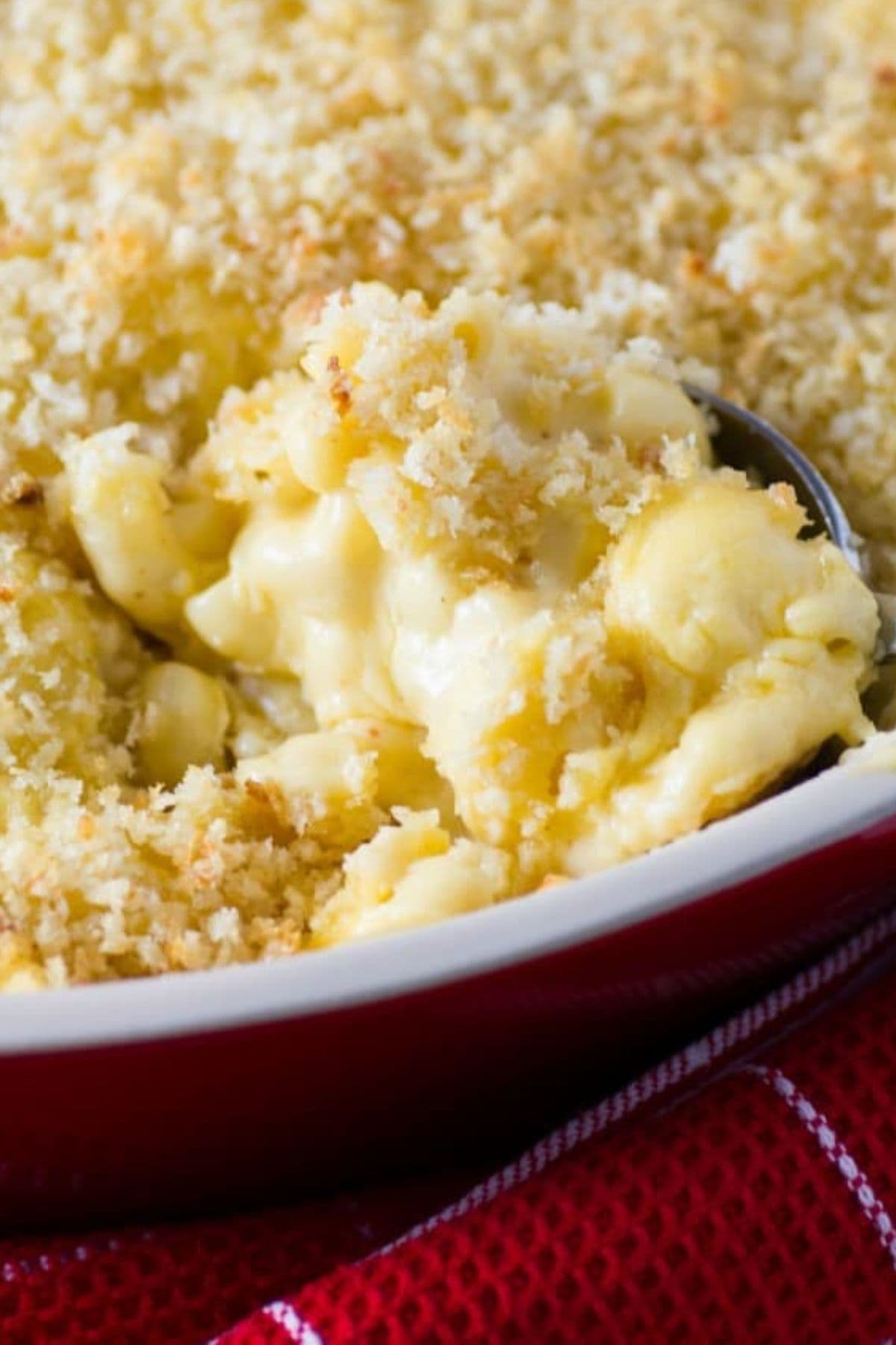 Scoop of classic mac and cheese being removed from a casserole dish.