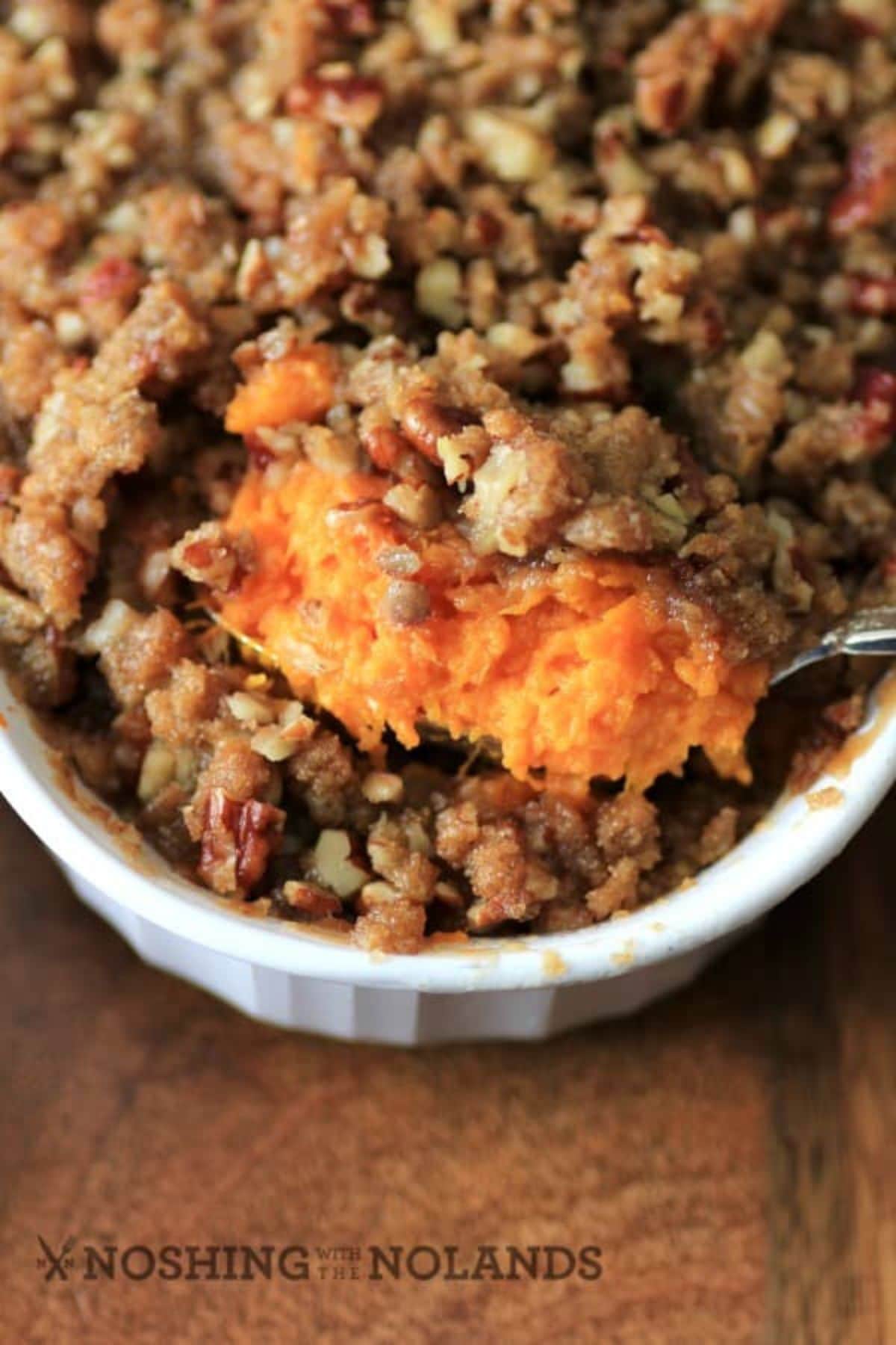 Spoonful of copycat Ruth's Chris sweet potato casserole held above a baking dish.