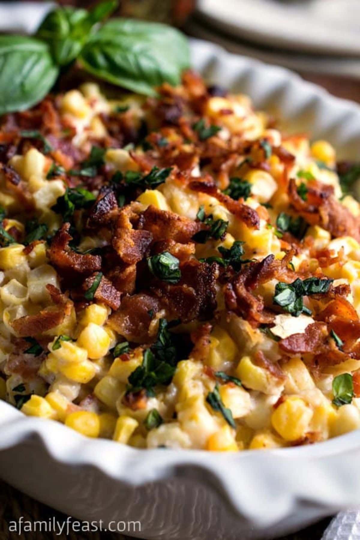 Baking dish full of cream and bacon casserole and garnished with crispy bacon pieces.