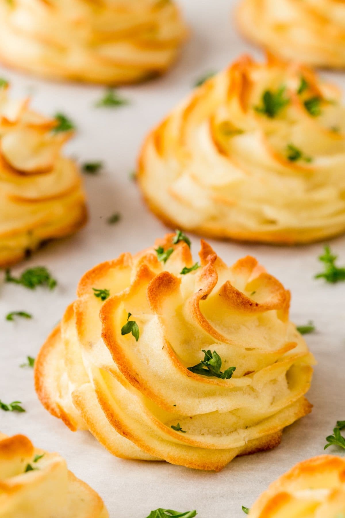 Baked dutchess potatoes on a parchment lined baking sheet.