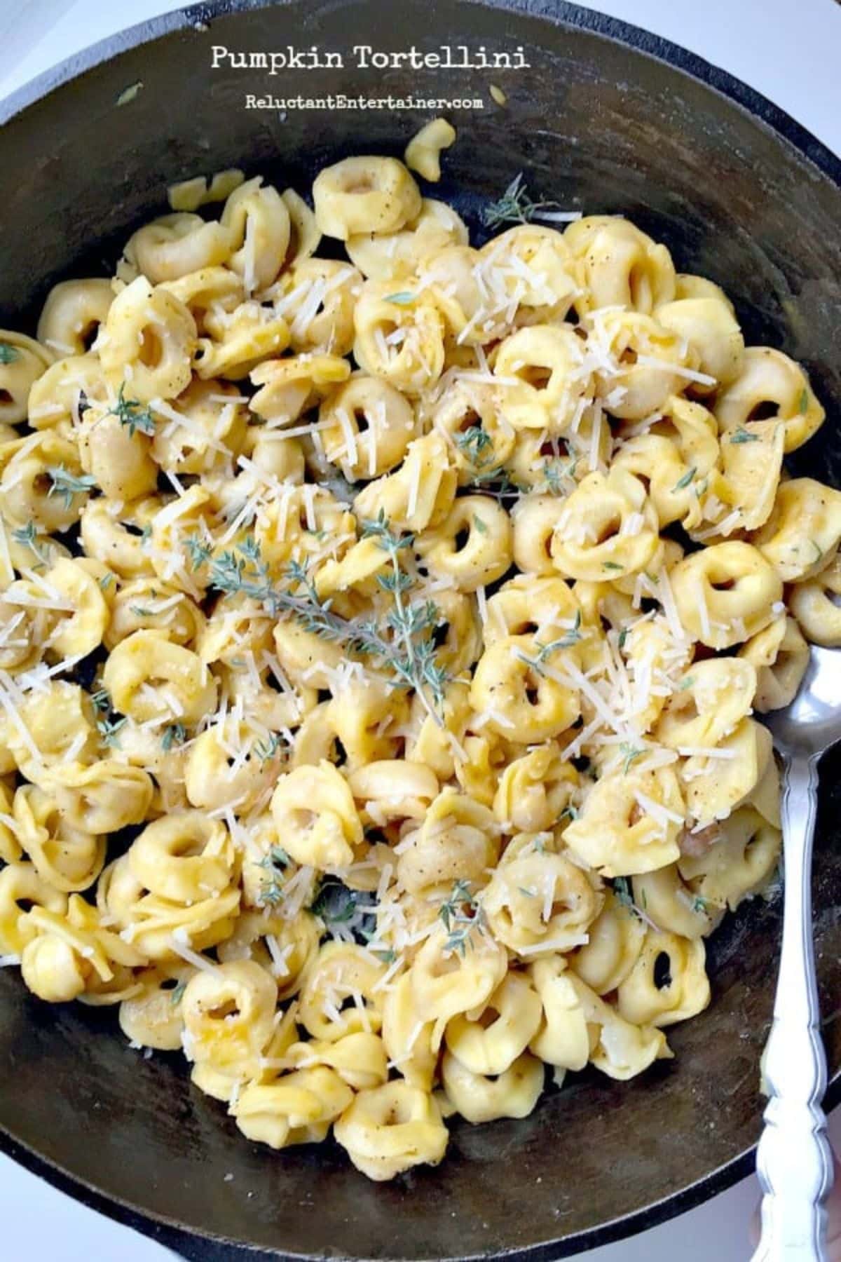 Bowl filled with pumpkin tortellini with a spoon in it.