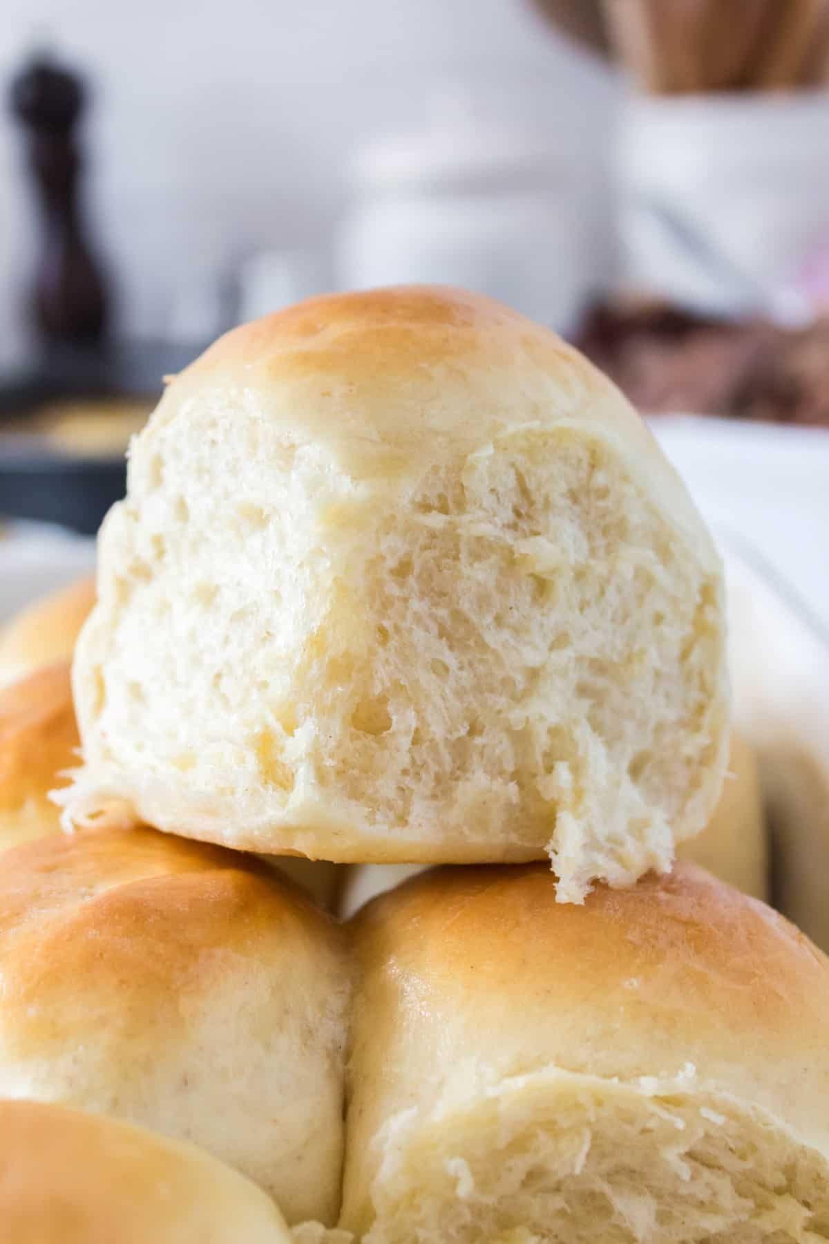 Sourdough dinner rolls stacked on top of each other on a serving platter.