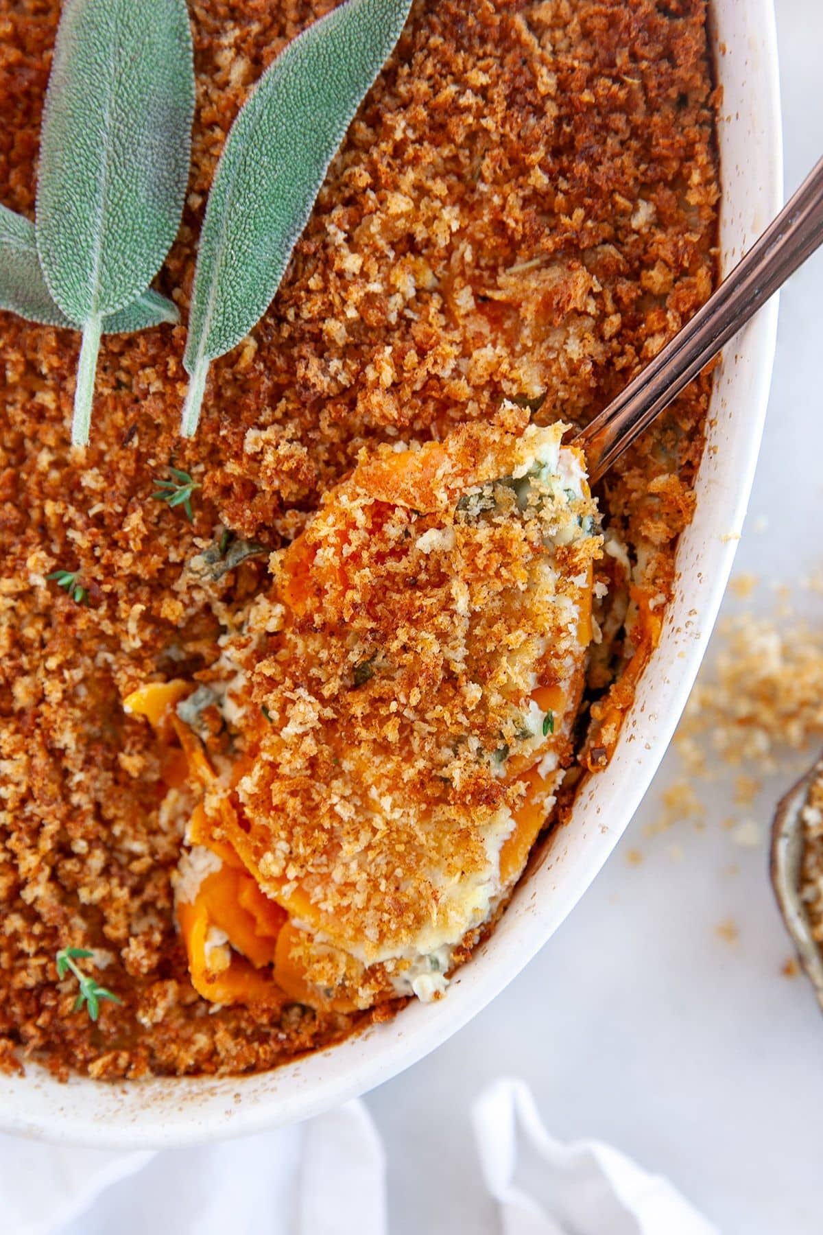 Spoonful of sweet potato au gratin being removed from a casserole dish.