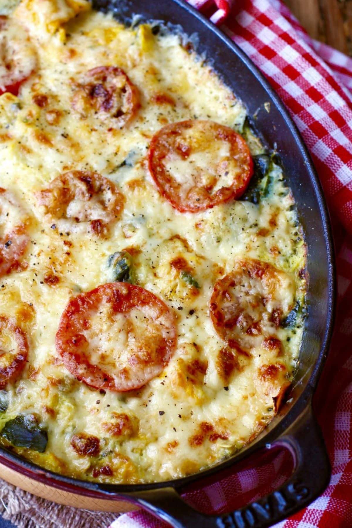 Baked zucchini tomato gratin in a serving dish on a table.