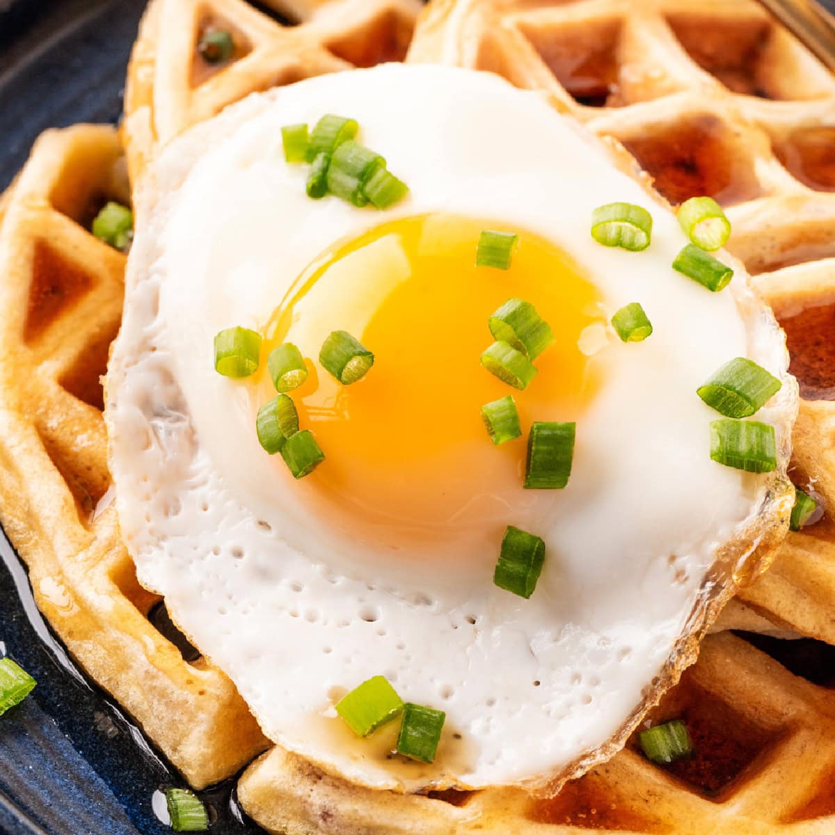 Square photo close-up of Bacon Waffles with a fried egg on top. 