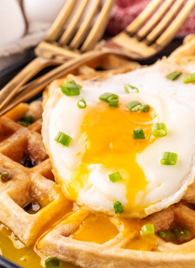 Broken yolk on an egg on waffles.