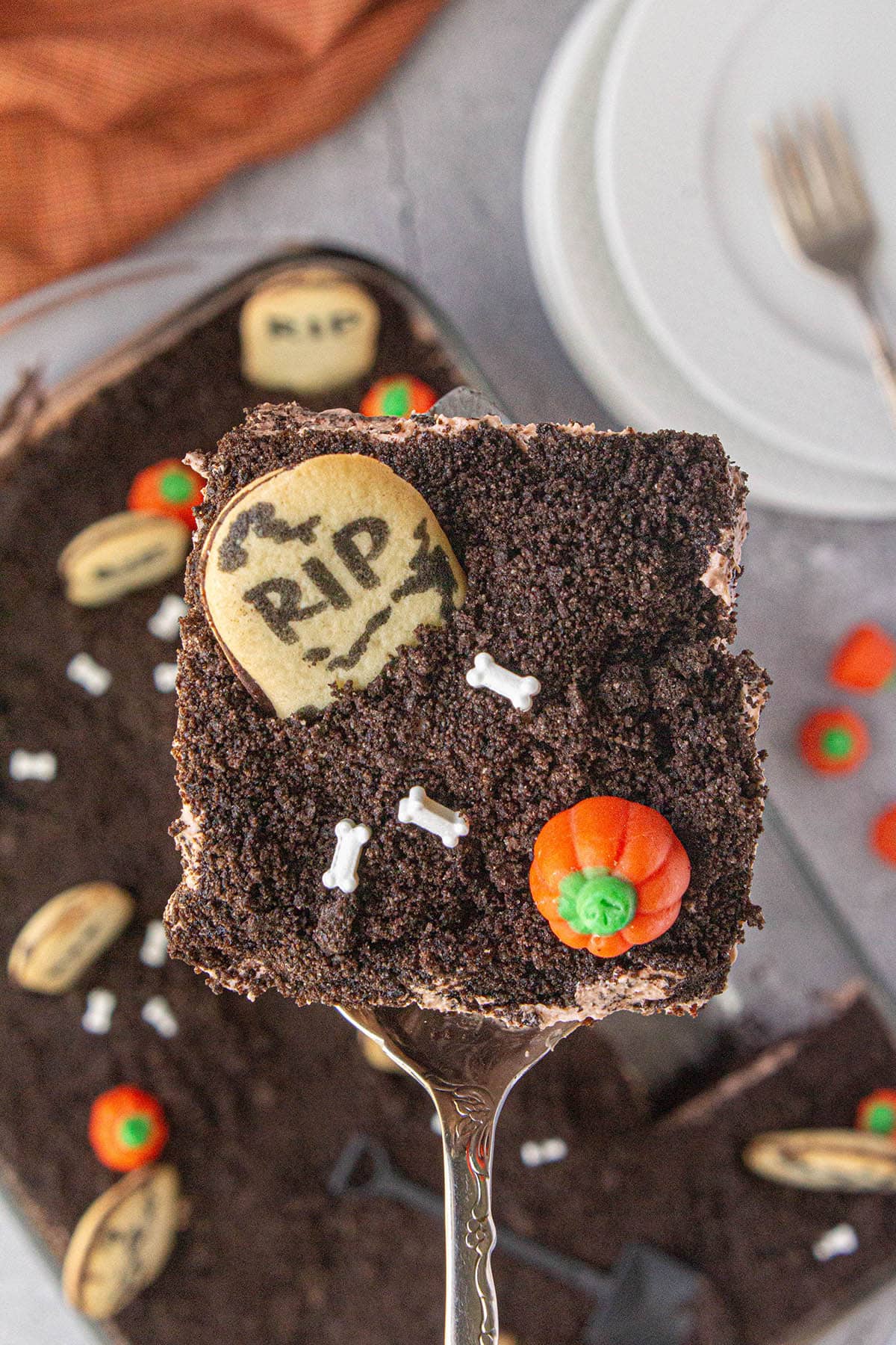 Slice of Graveyard Dirt Cake held in the air above the cake dish.