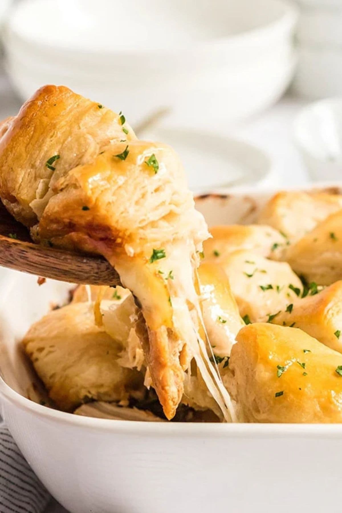 Wooden spoonful of french onion chicken casserole being removed from the baking dish.