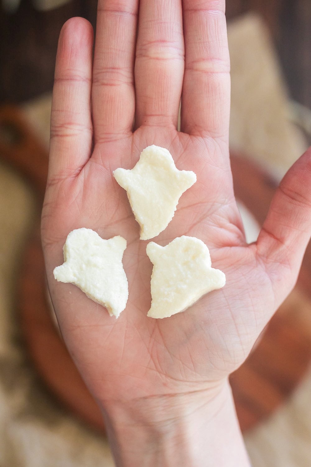 Three mozzarella ghosts in a palm of a hand. 