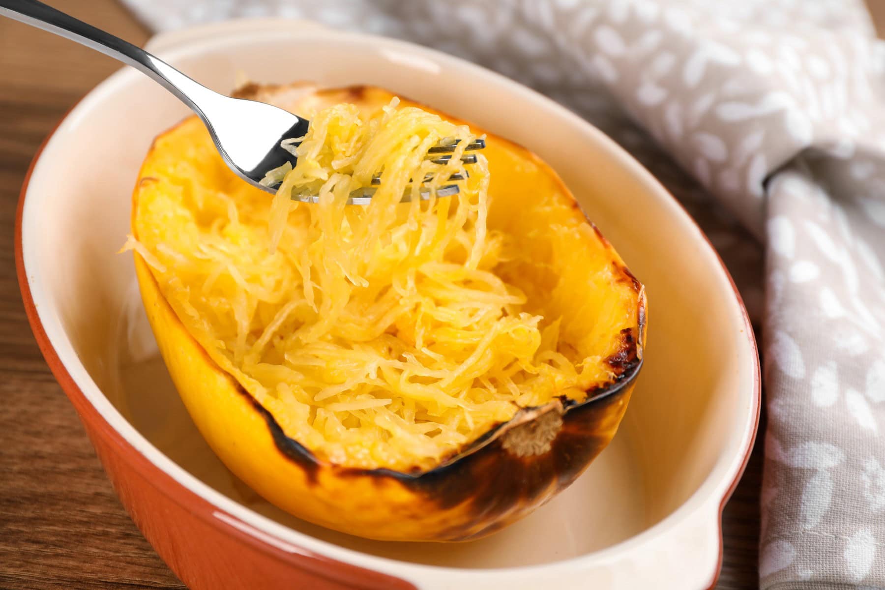 Cooked spaghetti squash with fork in dish.