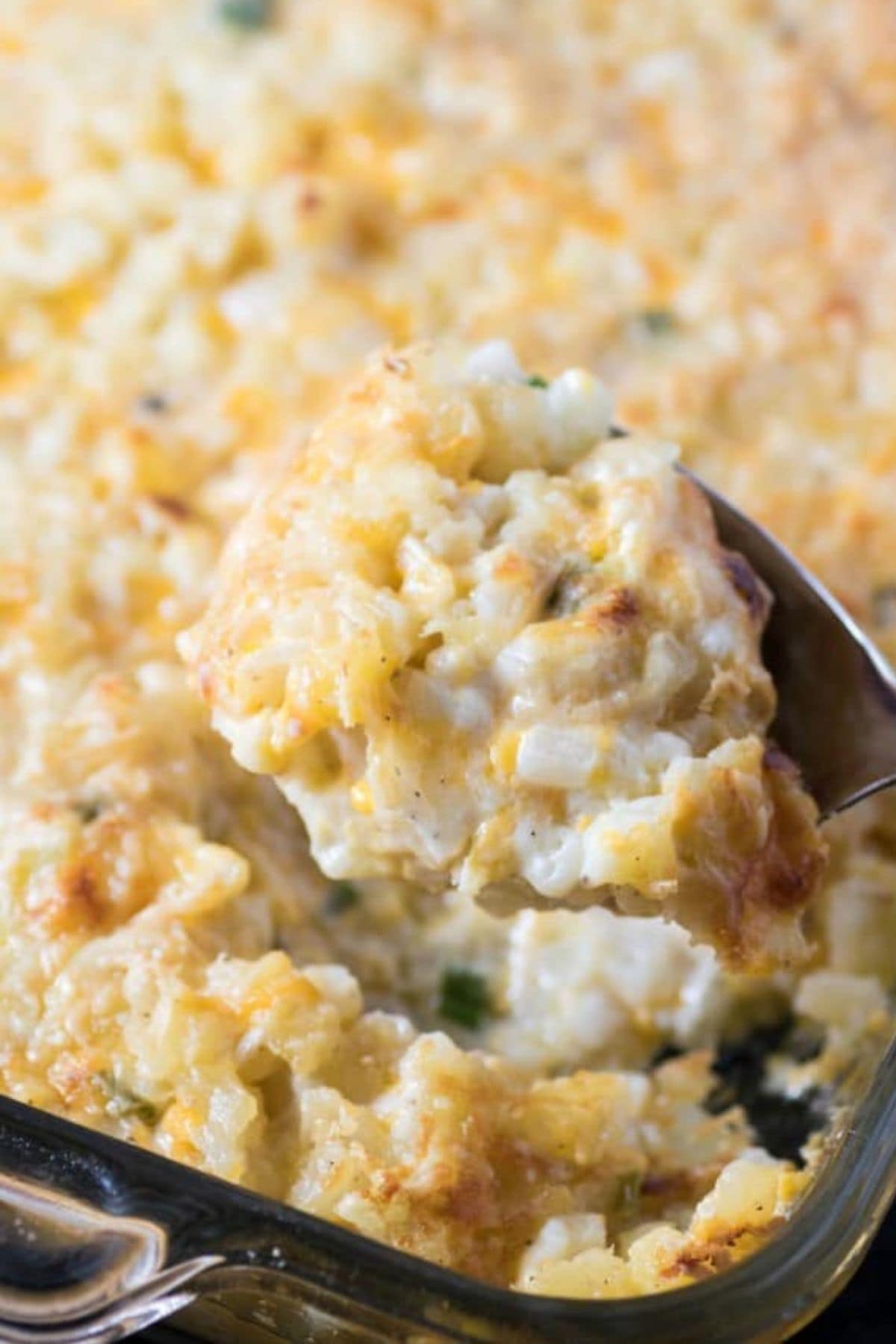 Spoonful of hash brown casserole being removed from a casserole dish.