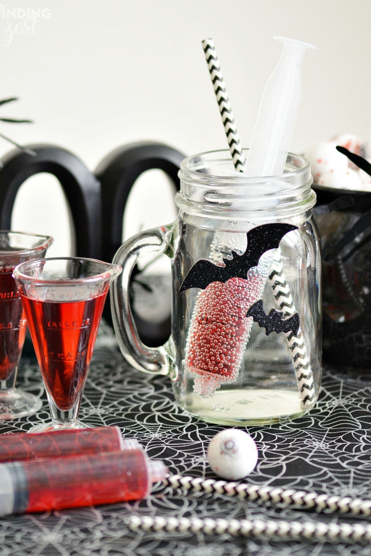 Mason jar with handle full of a halloween blood shot drink.