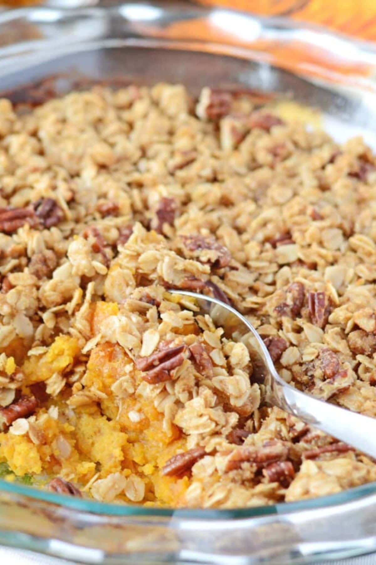 Round casserole dish filled iwth butternut squash casserole with a serving removed.