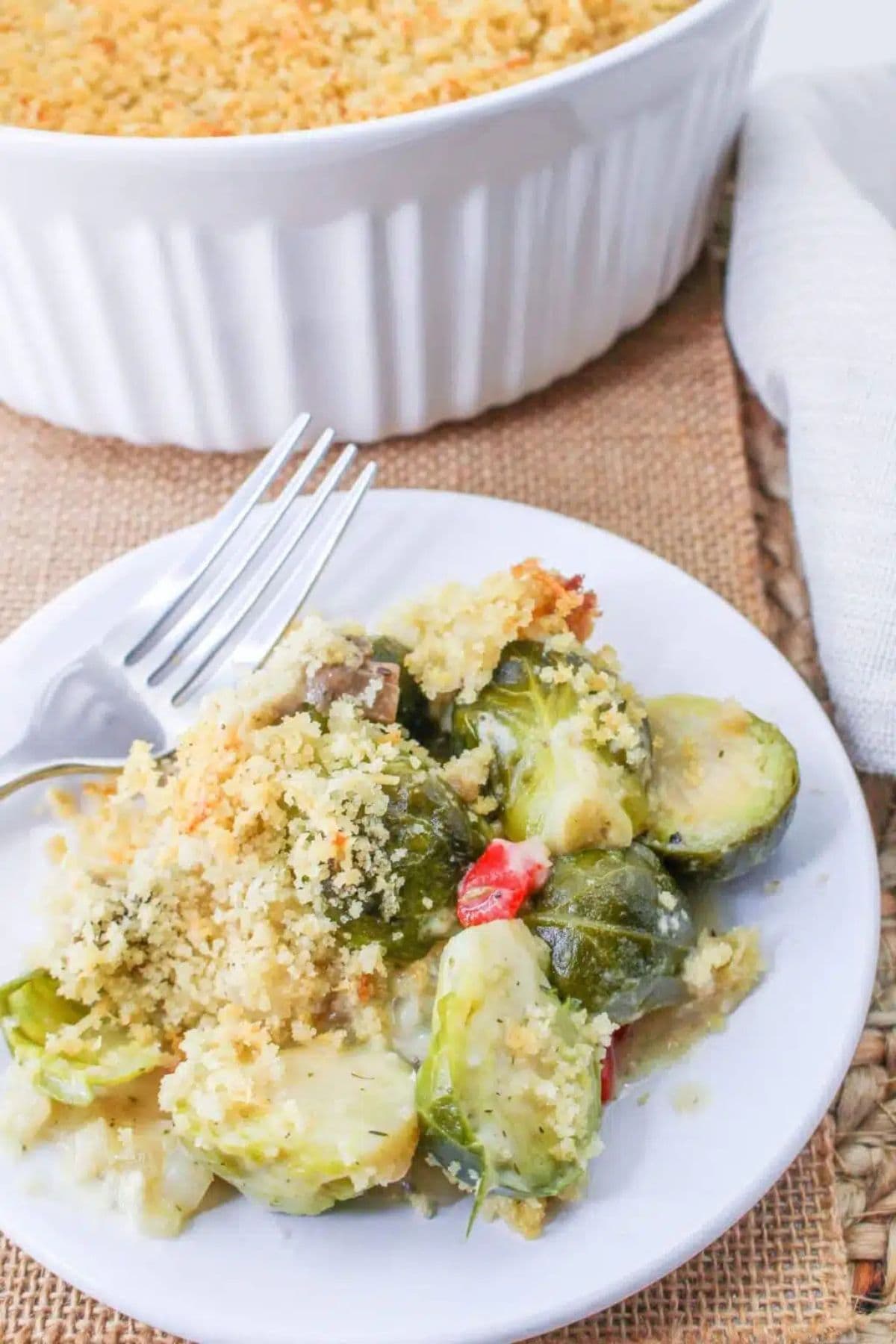 Small plate full of cheesy brussels sprouts casserole on a table ready to serve.