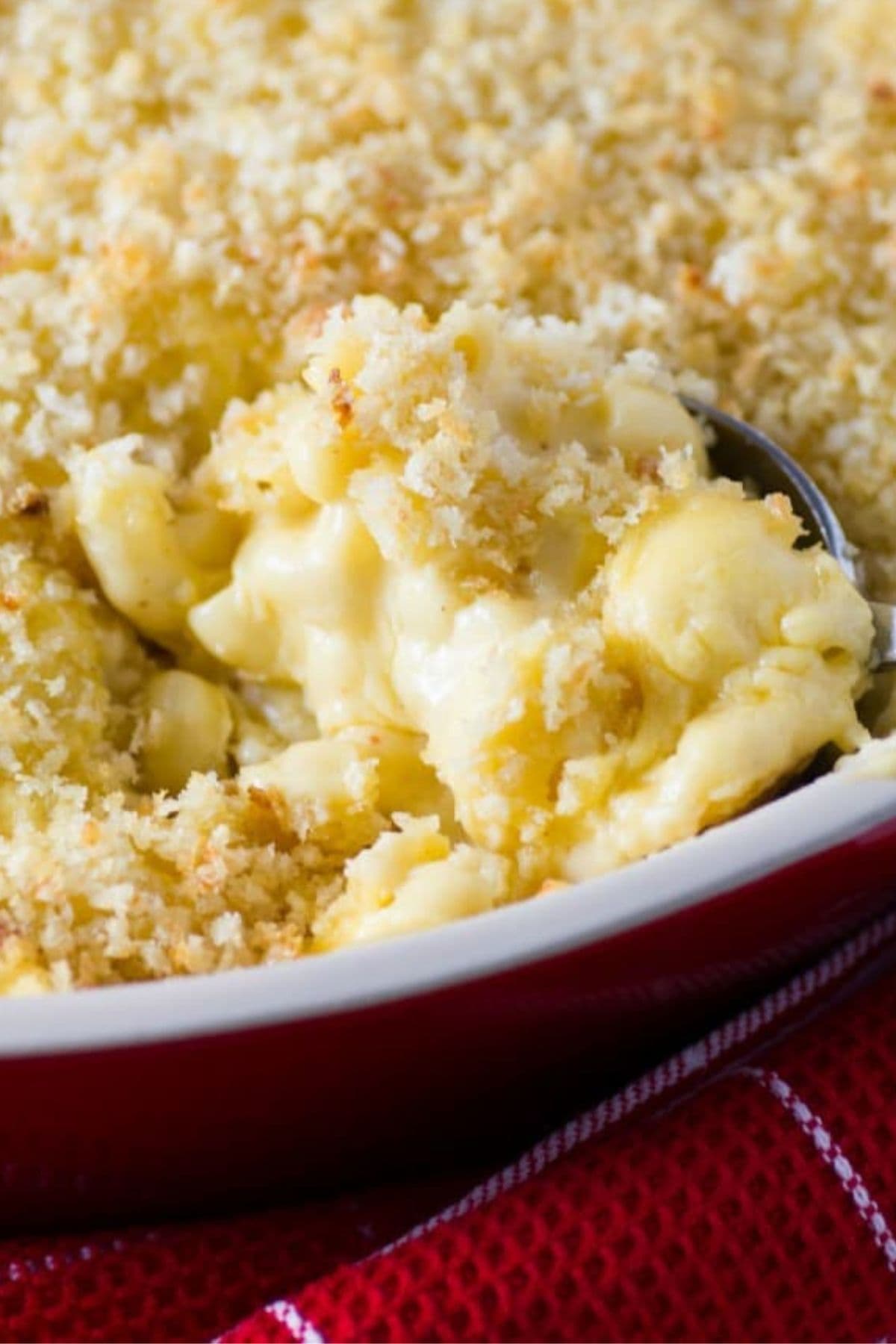 Spoonful of classic mac and cheese being removed from a casserole dish.