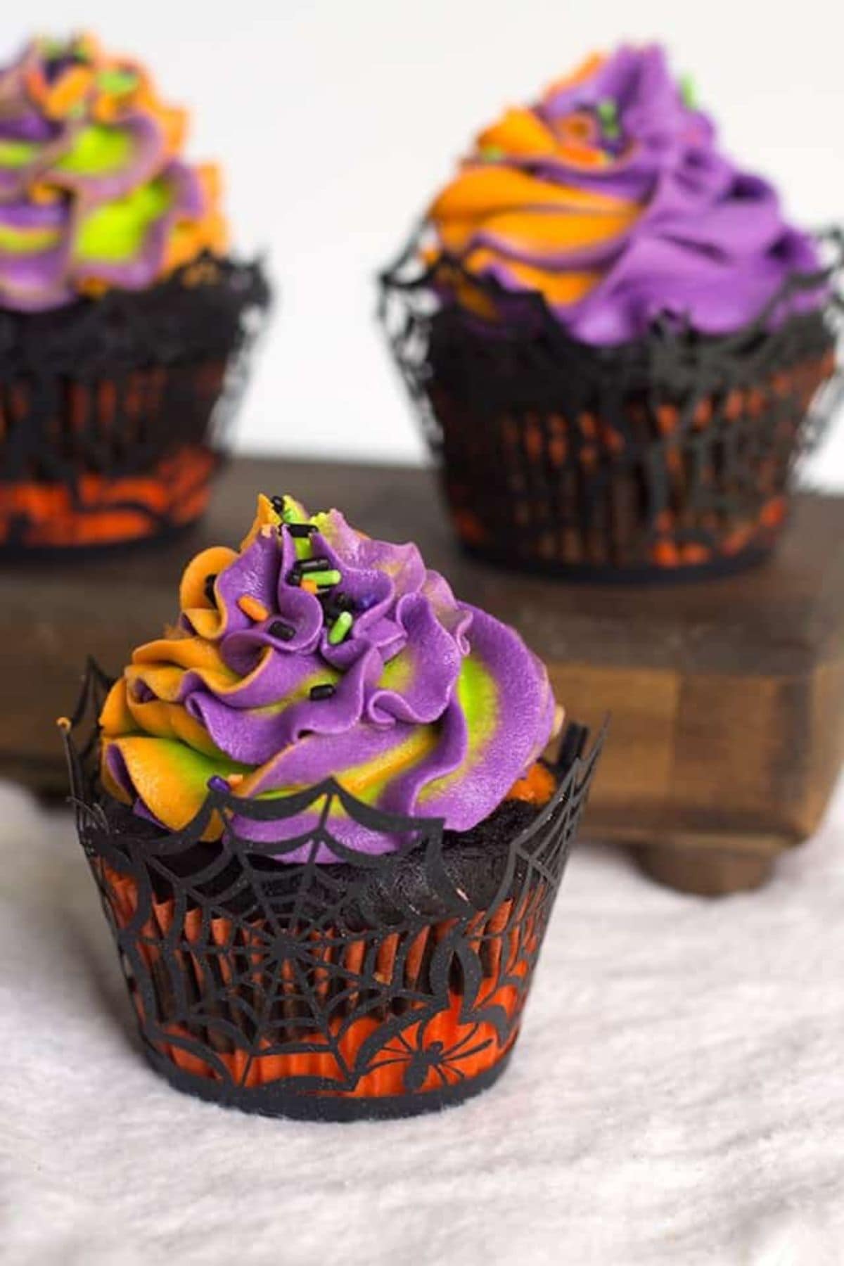 Three Halloween swirled cupcakes on a table.