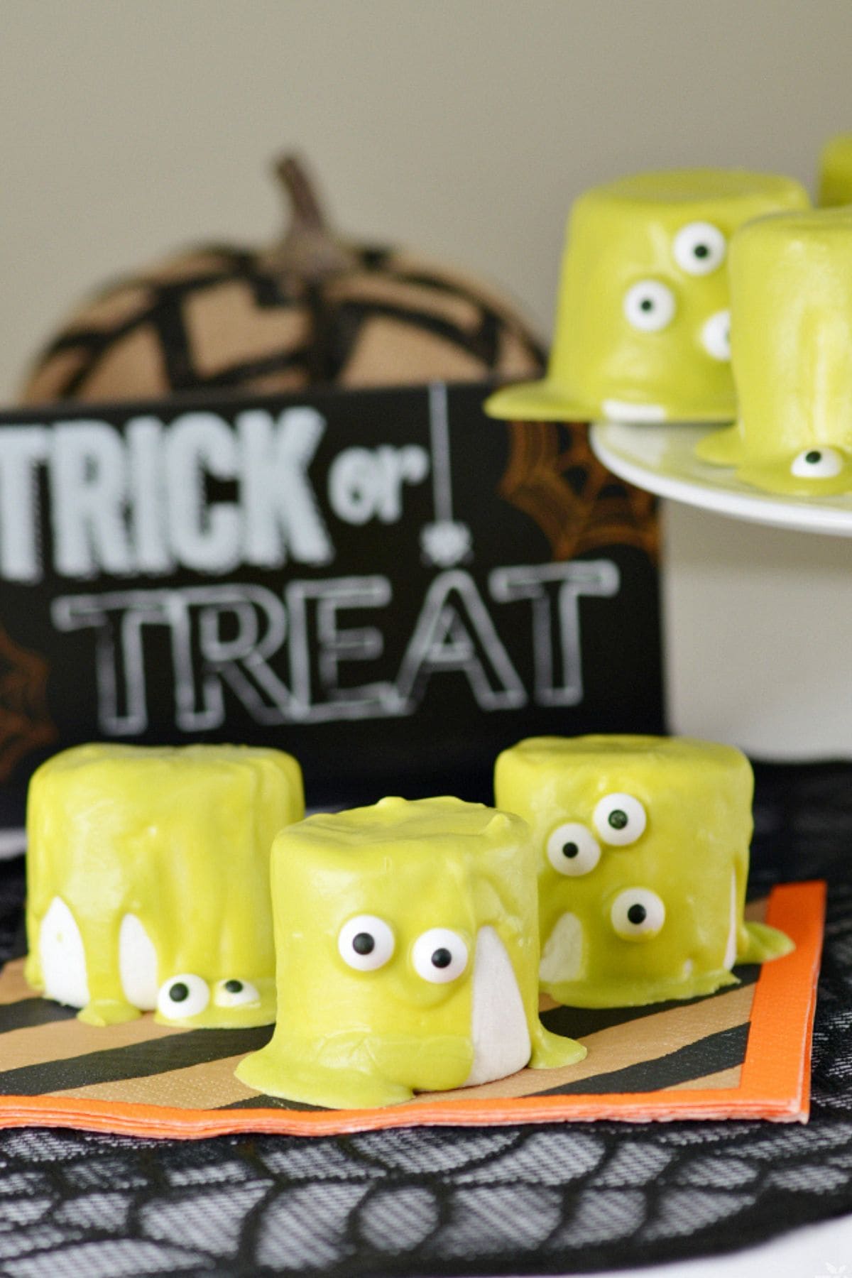 Three Monster Marshmallows on top of a Halloween napkin on a table.