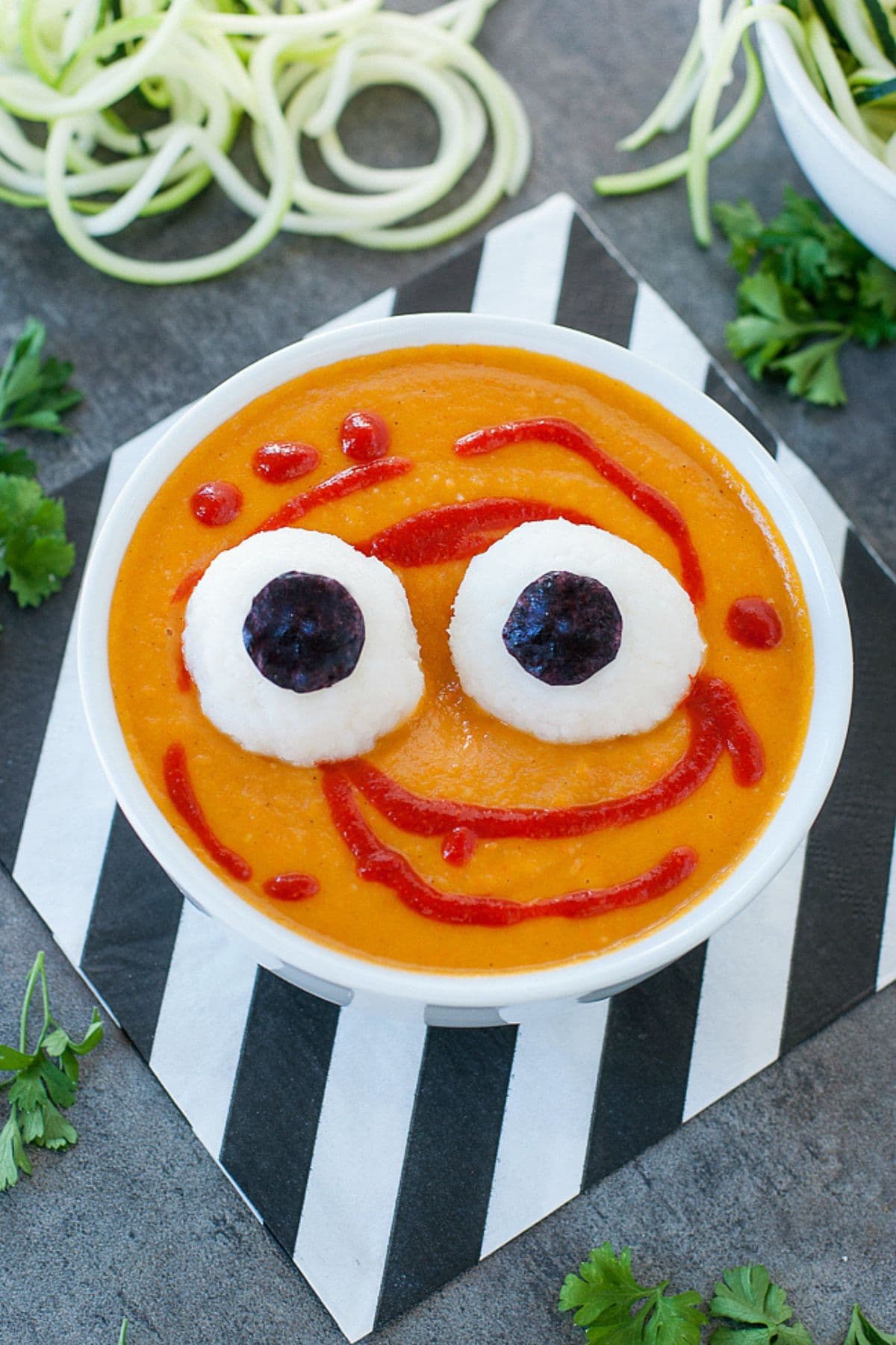 Bowl full of orange soup topped with eye balls.