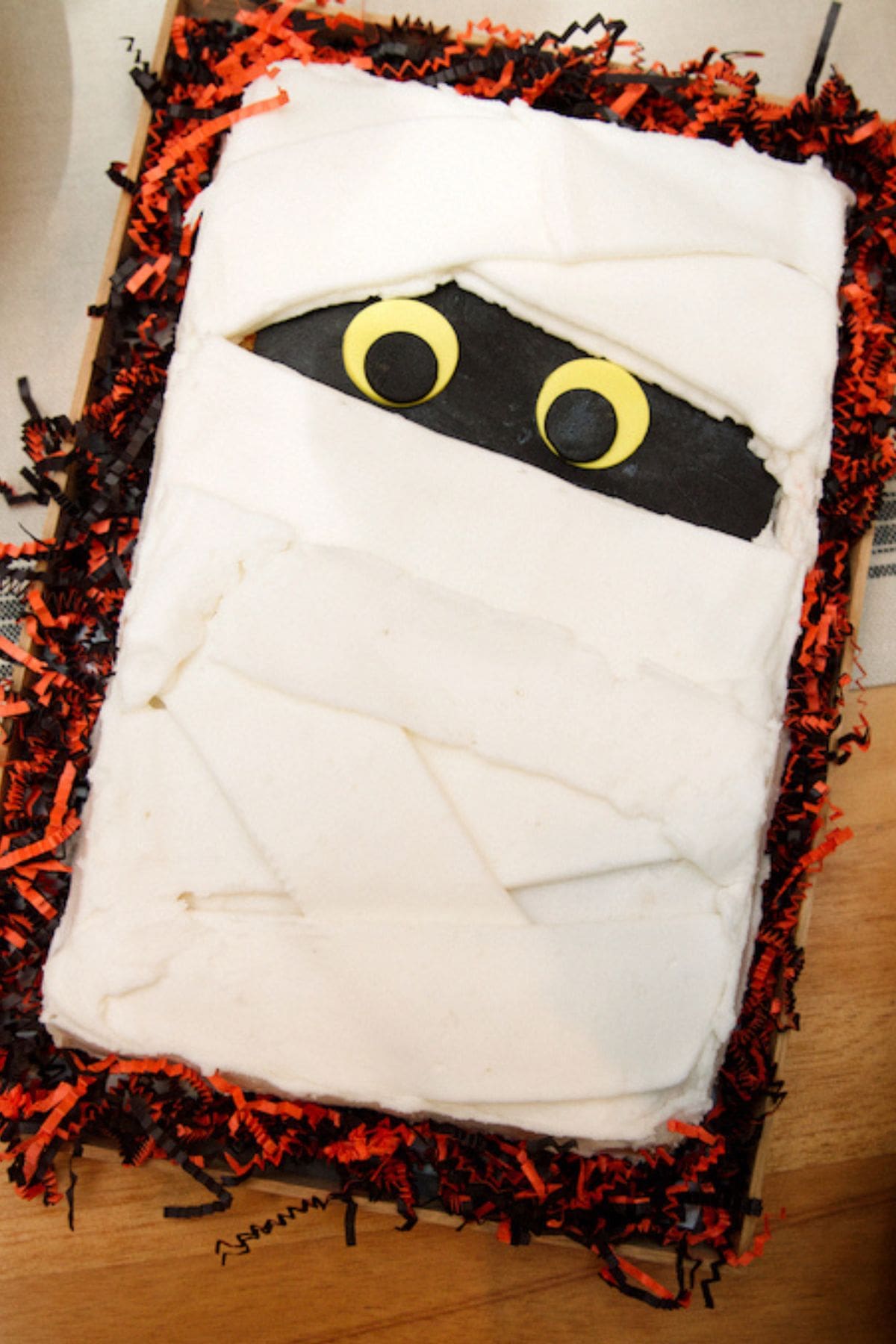 Sheet cake decorated like a mummy on a counter.