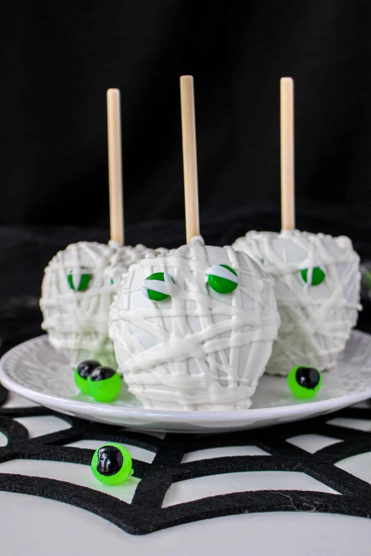 Three mummy candy apples on a plate.