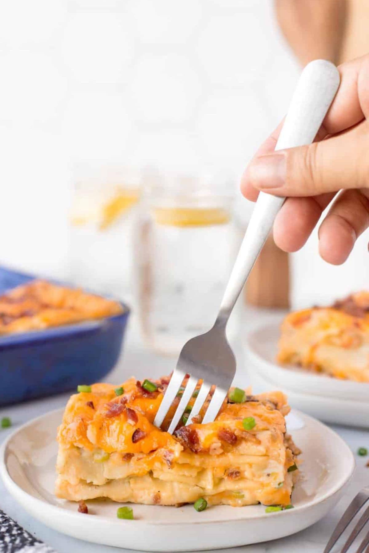 Small plate full of pierogi casserole with a bite being removed with a fork.